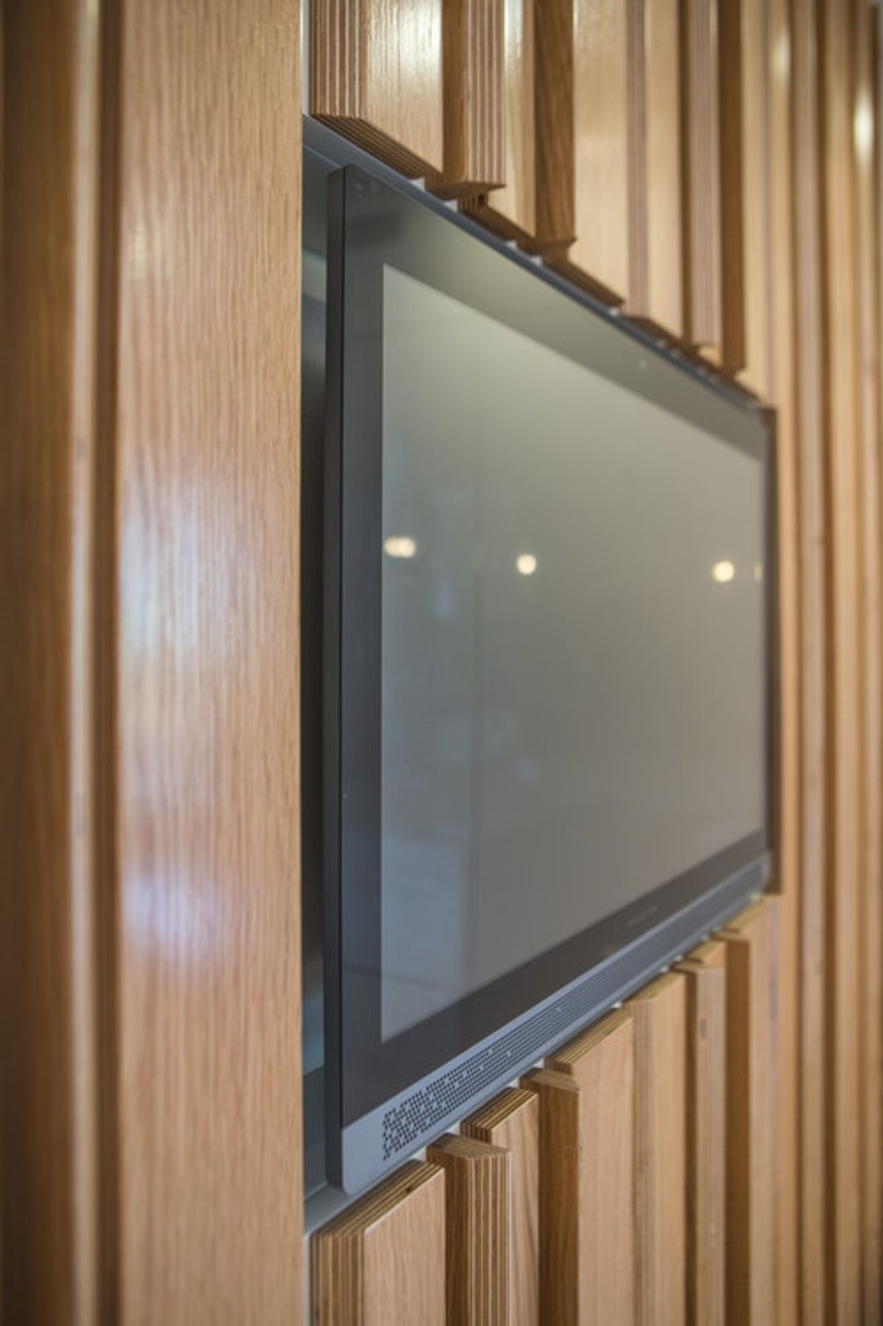The digital screen inset into the oak plywood feature wall.