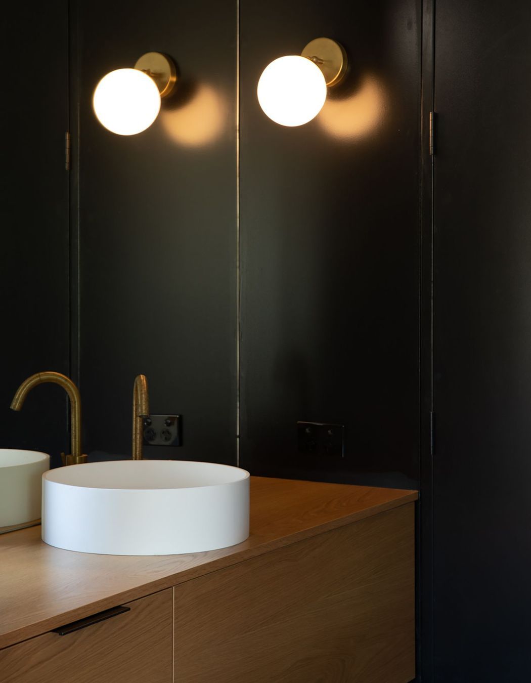 A moody bathroom utilises natural materials and feature lighting.