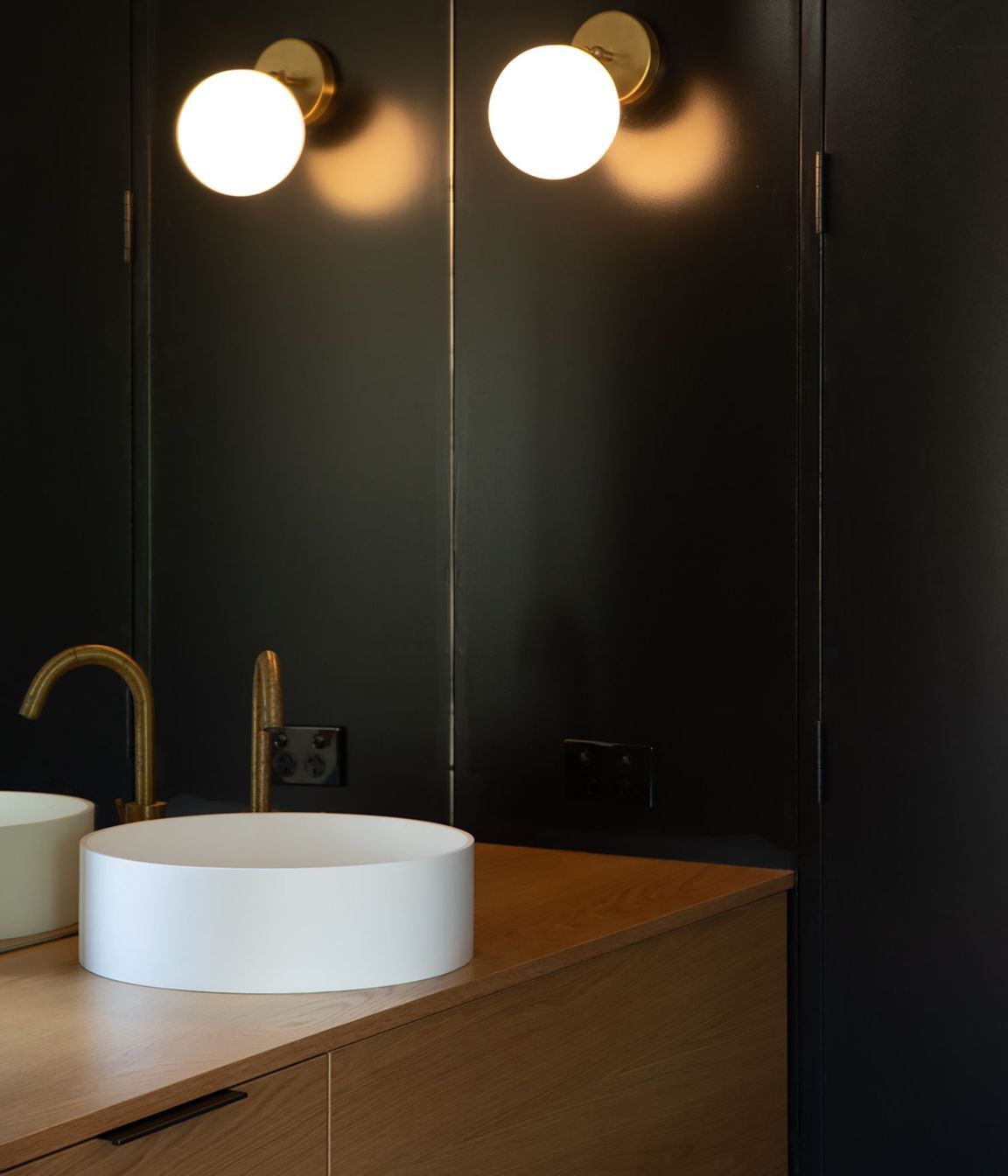 A moody bathroom utilises natural materials and feature lighting.