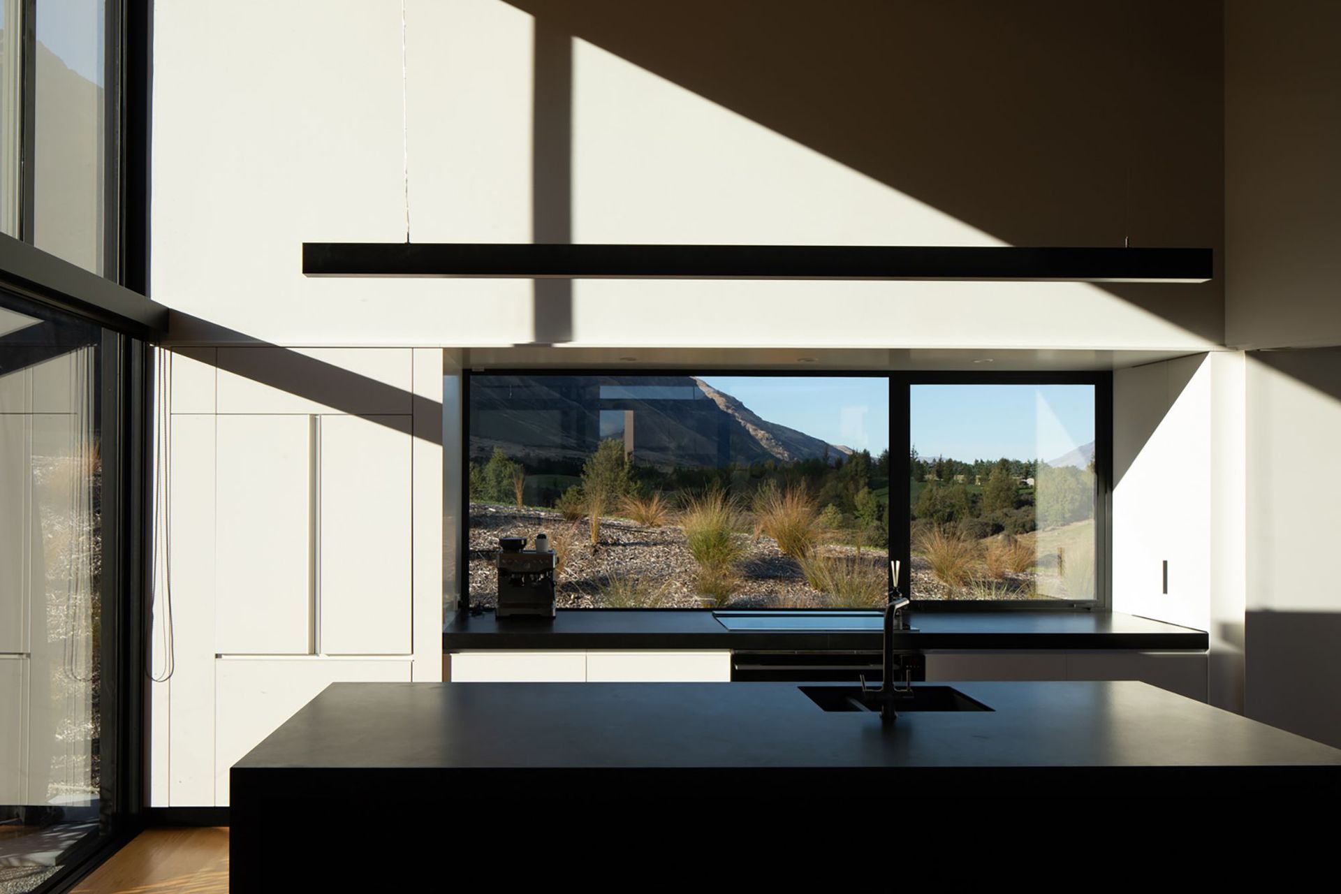 The monochromatic kitchen forms the perfect backdrop for light that plays across the space, creating moving shadows.
