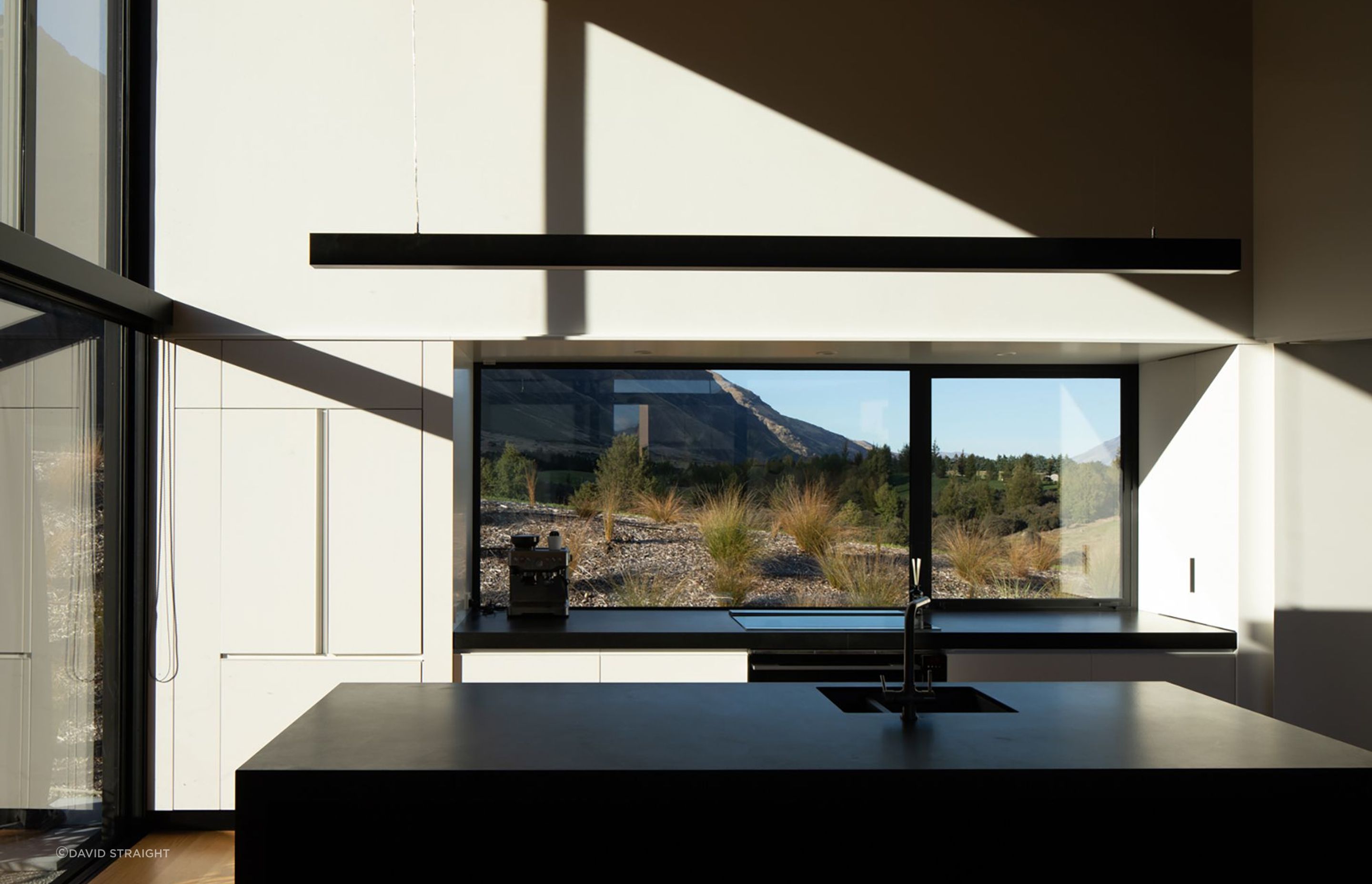 The monochromatic kitchen forms the perfect backdrop for light that plays across the space, creating moving shadows.