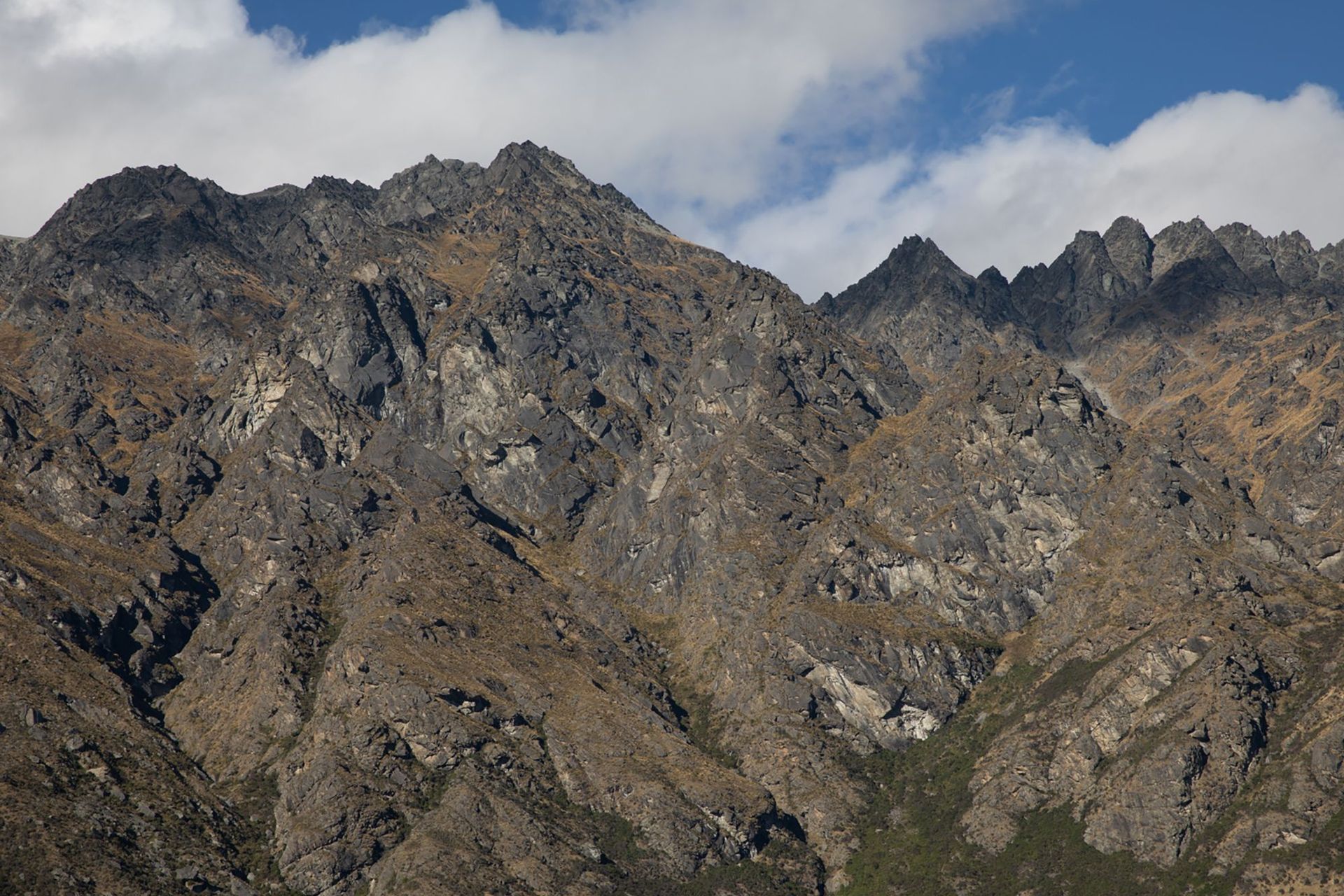 A view of The Remarkables mountain range during summer, without snow on its peaks.