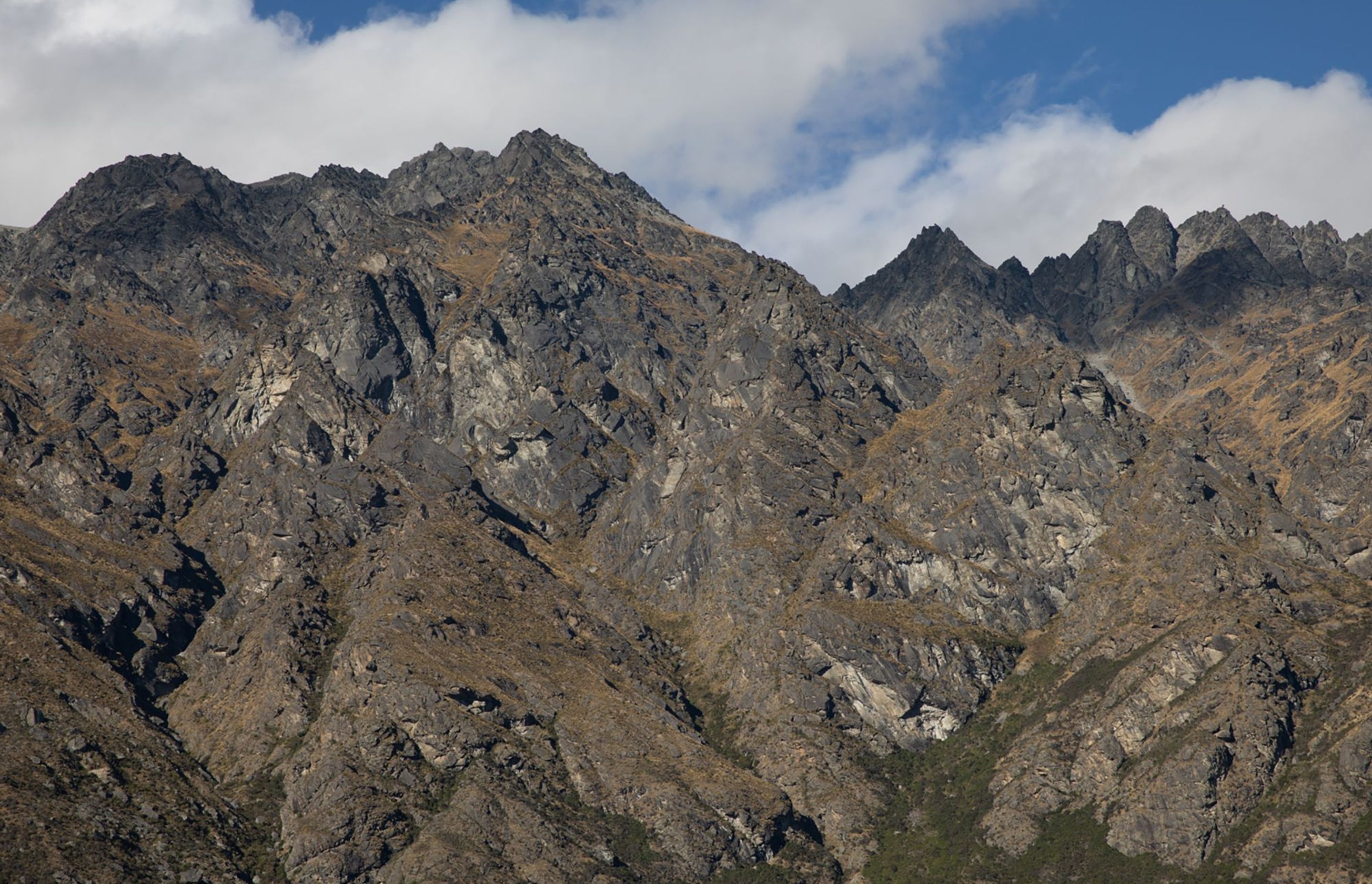 A view of The Remarkables mountain range during summer, without snow on its peaks.