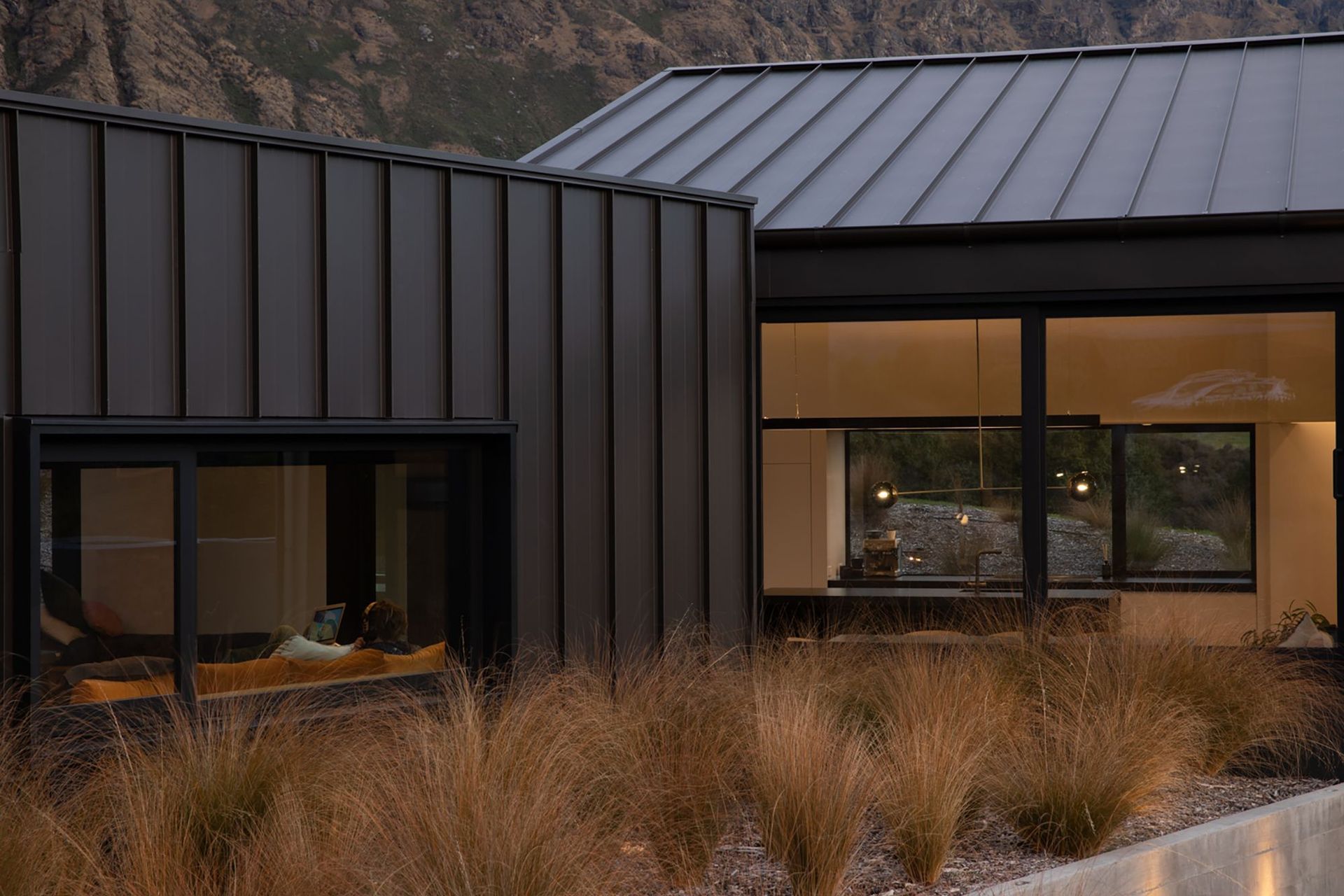 View of the media lounge (left) and the dining space and kitchen (right), showing the level changes from one area to the other.