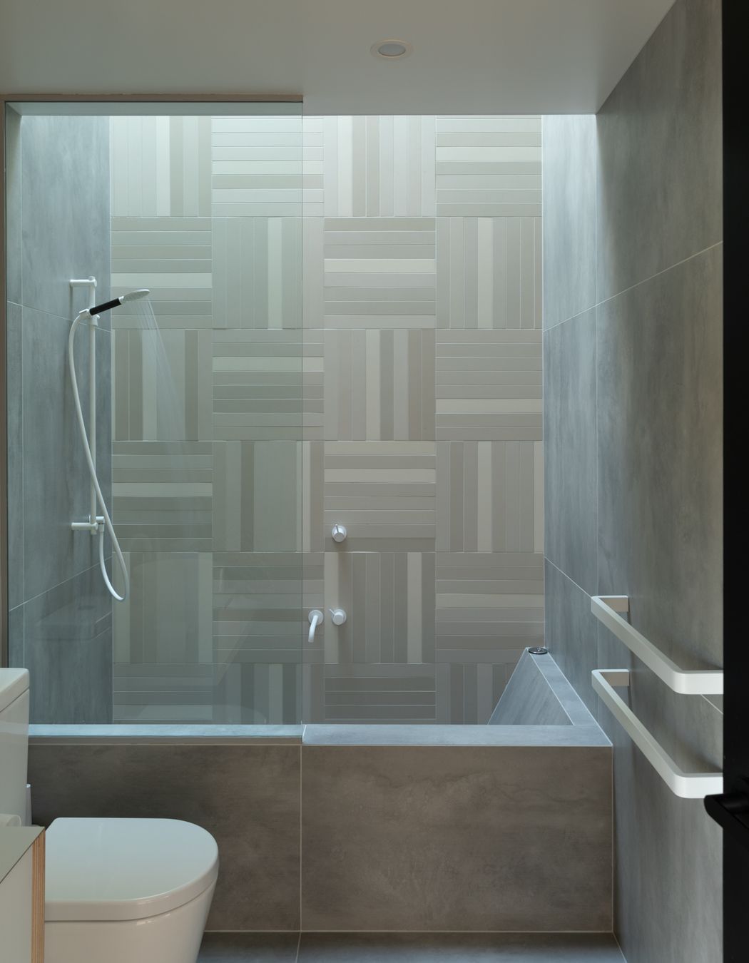Rectangular mosaic tiles and white tapware create an elegant bathroom.