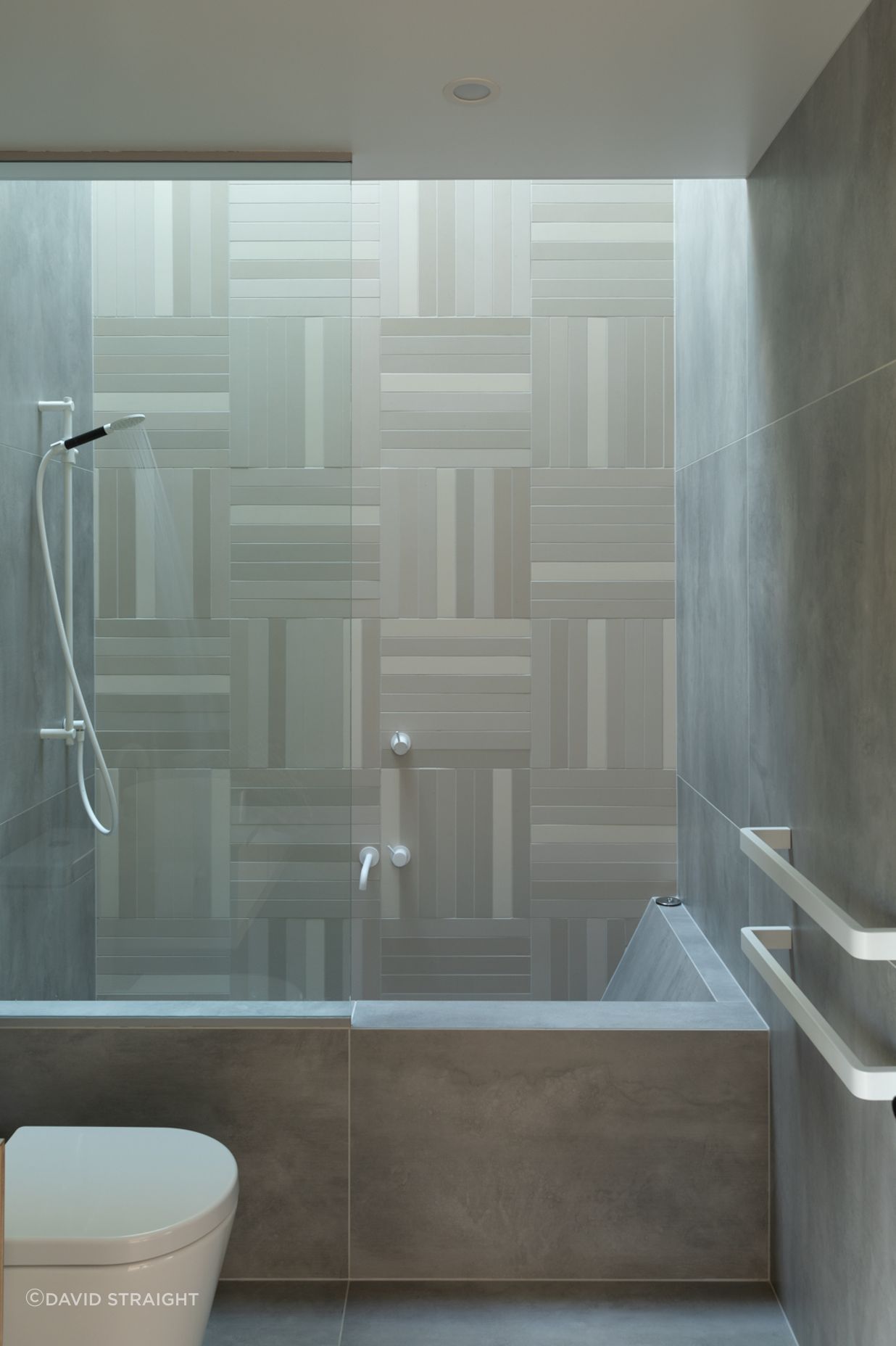 Rectangular mosaic tiles and white tapware create an elegant bathroom.