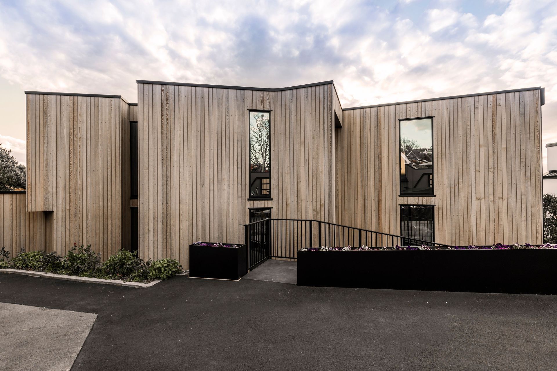From the driveway, facing east, the two-storeyed cedar-clad house appears like a solid form that is anchored firmly to the grou