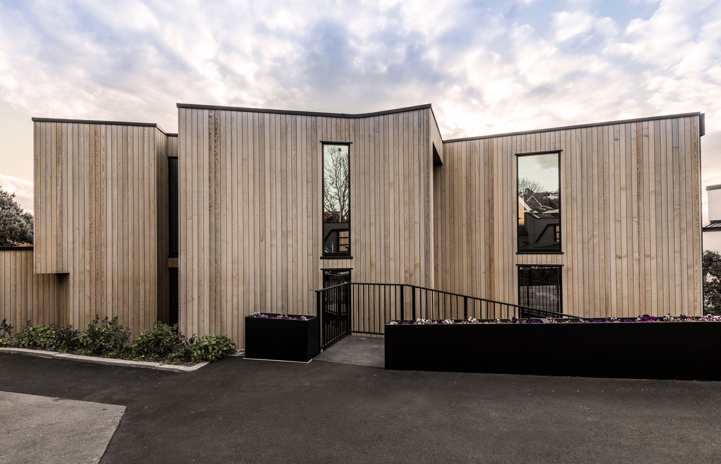 From the driveway, facing east, the two-storeyed cedar-clad house appears like a solid form that is anchored firmly to the grou