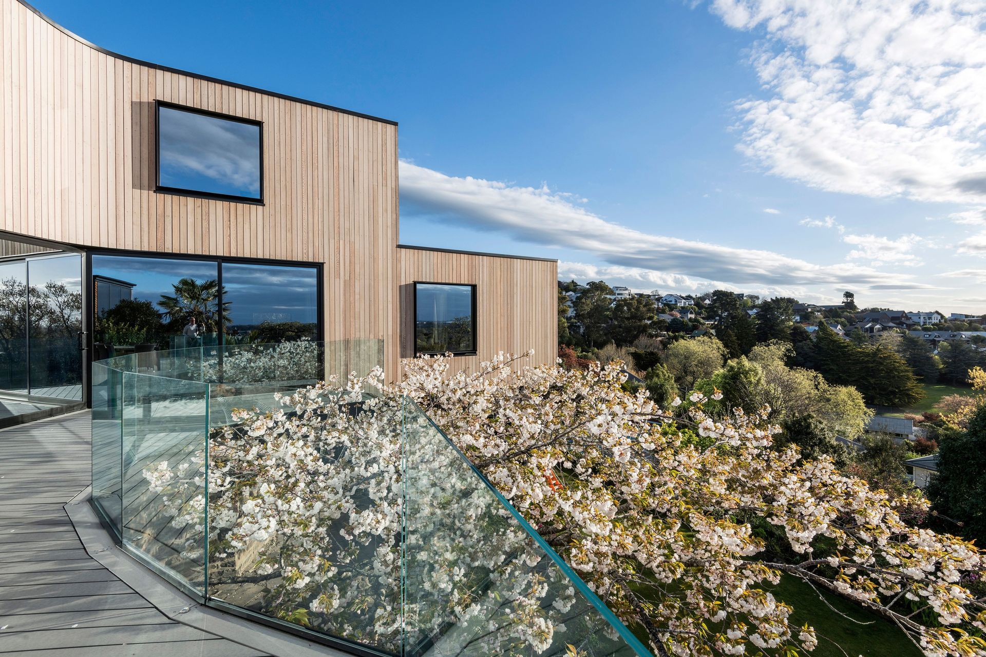 The plan of the home curves around a 100-year-old cherry blossom tree with the extensive decking around the ground floor almost nestled among the tree top.