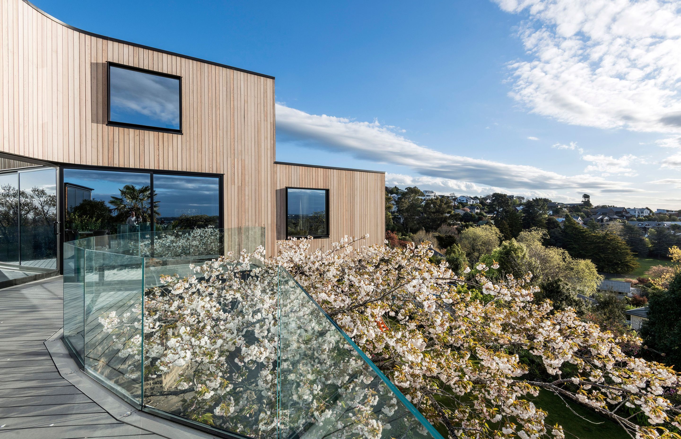 The plan of the home curves around a 100-year-old cherry blossom tree with the extensive decking around the ground floor almost nestled among the tree top.