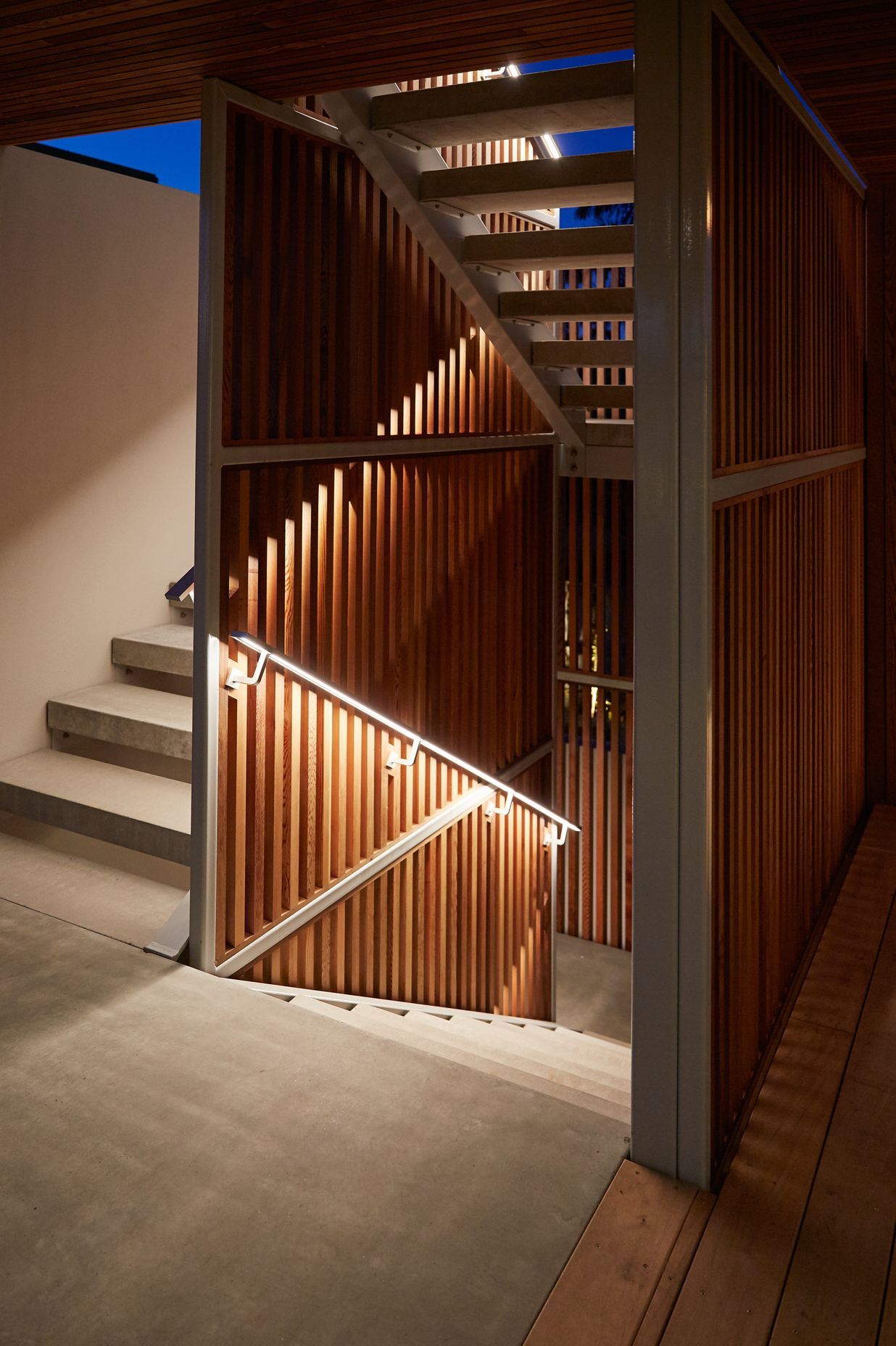 At night, integrated lighting within the custom-built handrails on the external staircase interacts with the cedar screen to transform the staircase into a light sculpture.