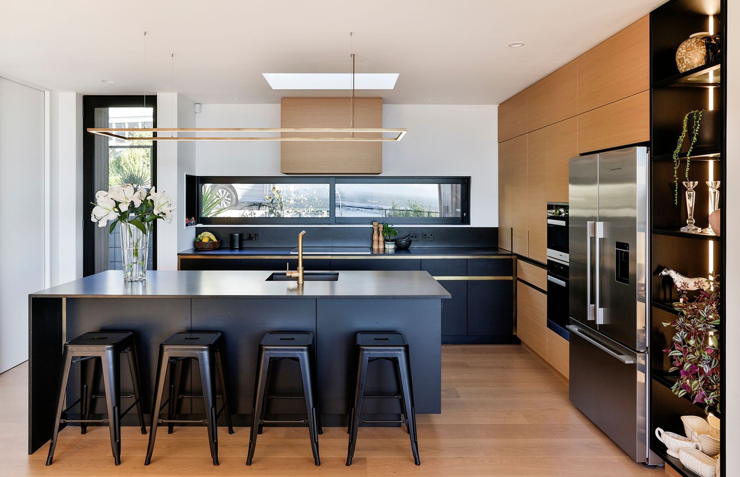 A skylight over the kitchen draws light into the space, aided by a rectilinear feature light over the benchtop, The main entrance is on the left hand side.