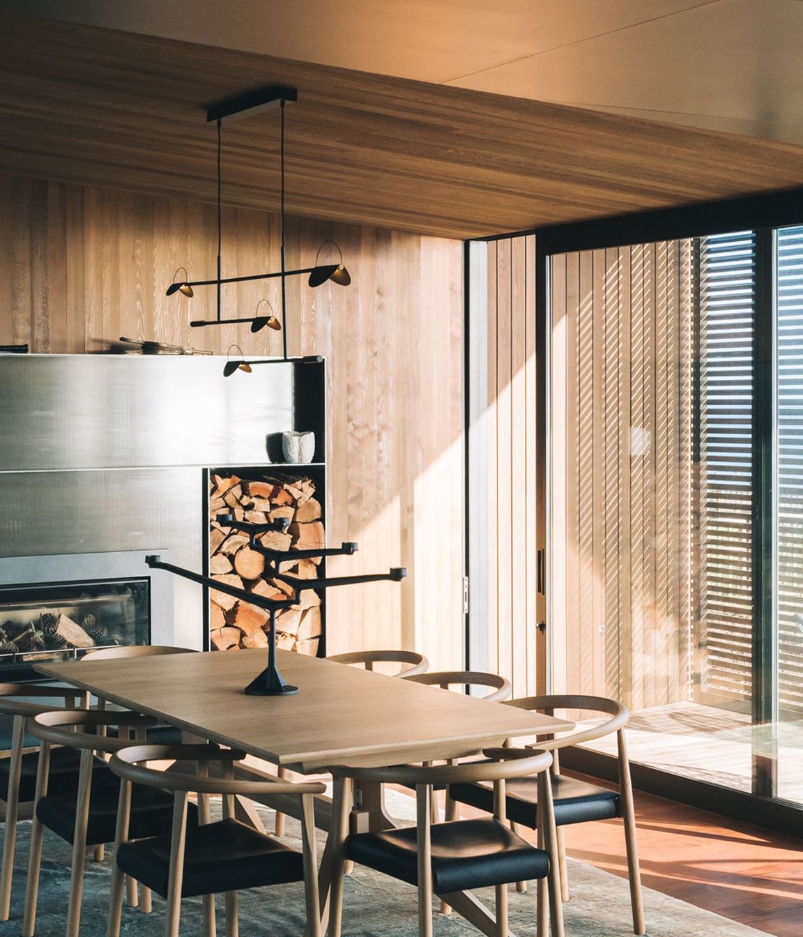 A woodfire is framed by custom steel cabinetry that contrasts the timber used elsewhere.