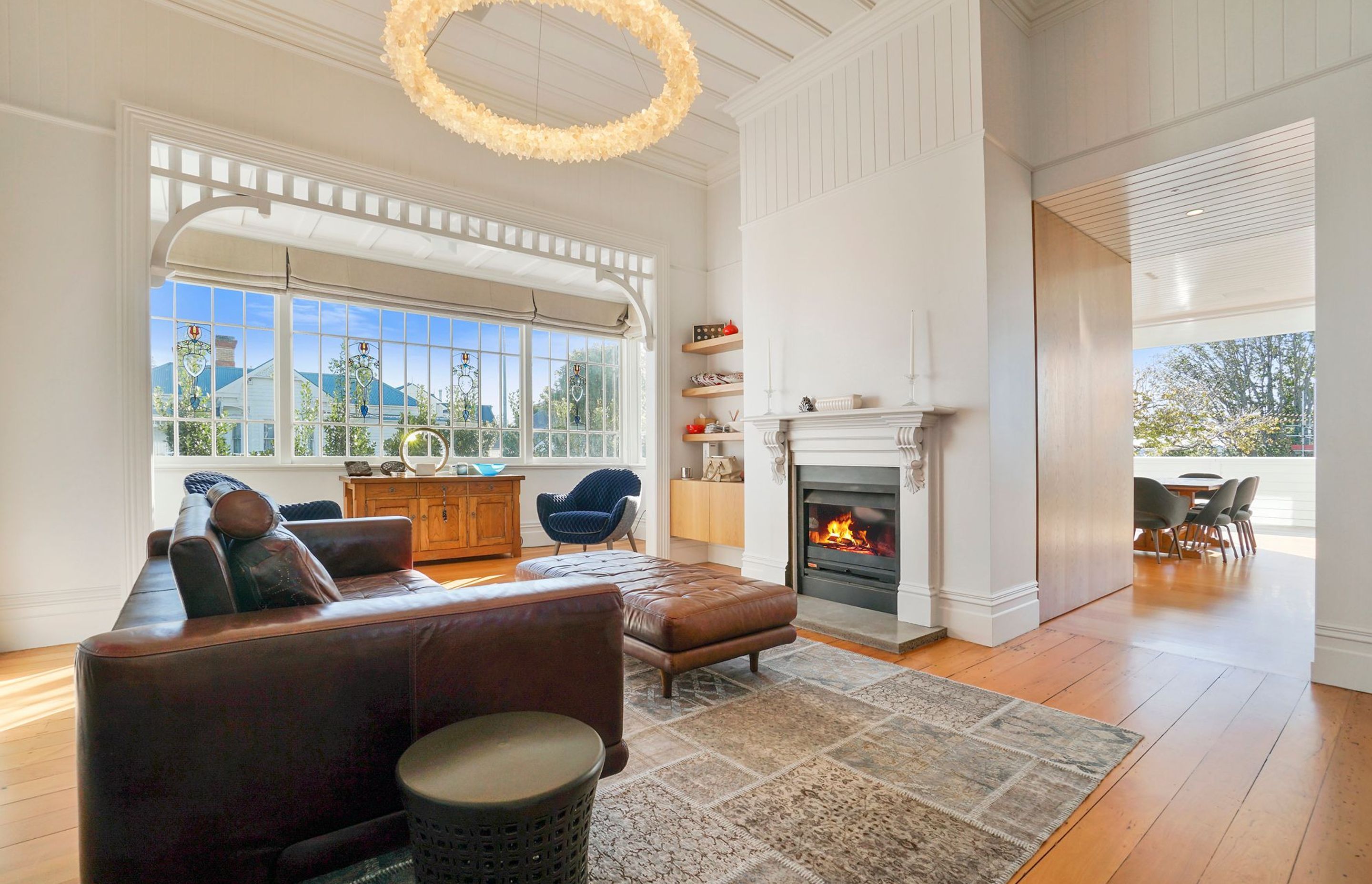 The home has been treated to a loving restoration by the builders, with mindful timber work seen throughout the front of the house. This is exhibited in the upstairs living room, where the beautiful villa meets a luxurious twist, with decadent crystal lighting conversing with Kauri flooring and vintage led light windows.