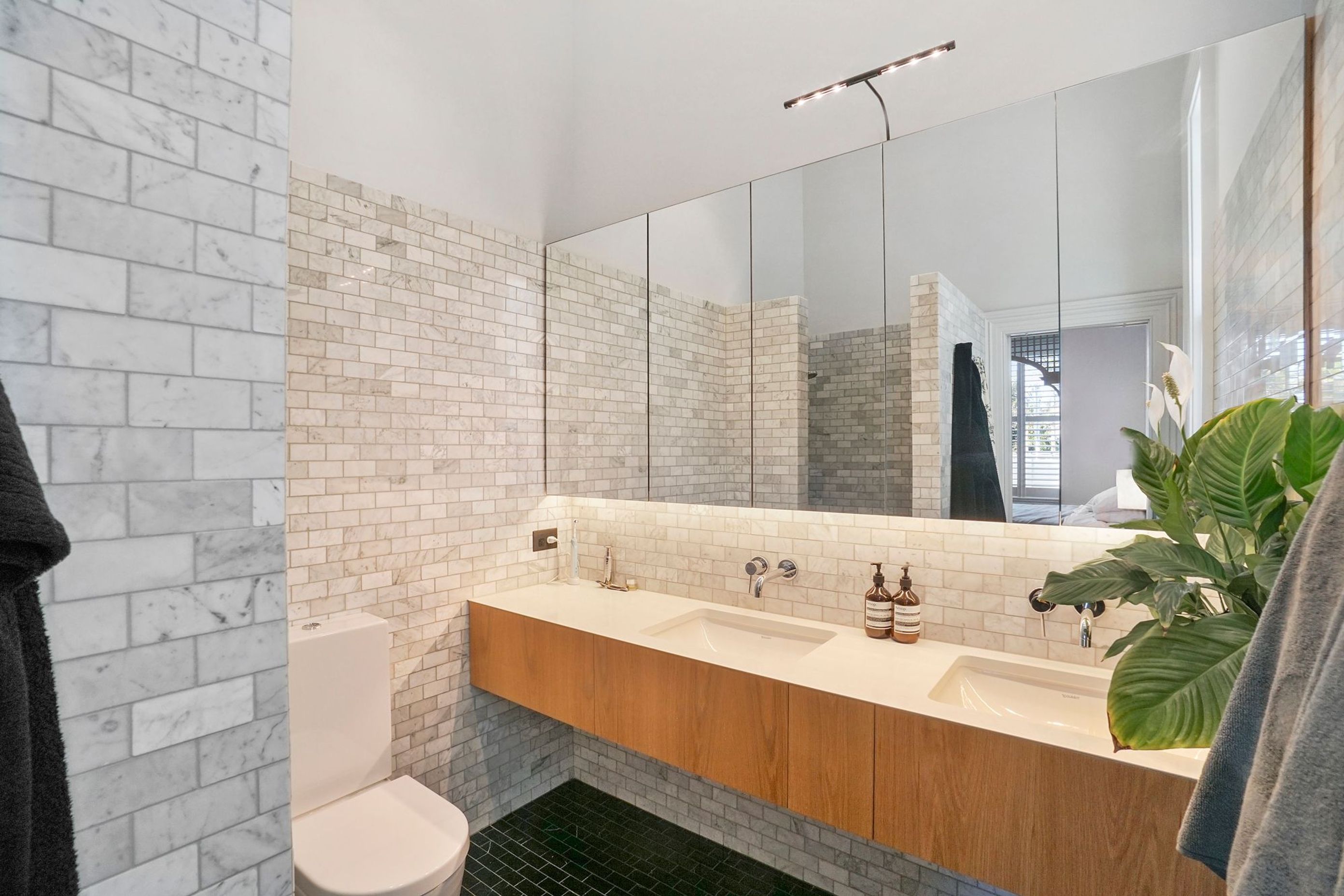 A mixture of sophisticated America Oak and natural stone keep the bathrooms in touch with the rest of the home’s presence and memorable feel.