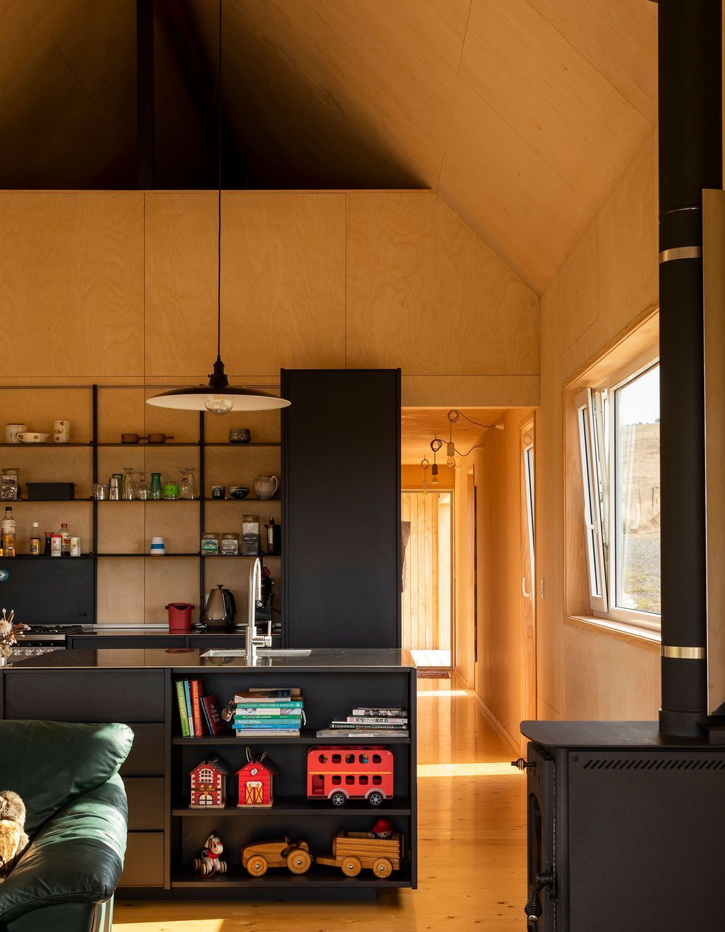 An all-black kitchen provides a strong contrast against the light timbers.