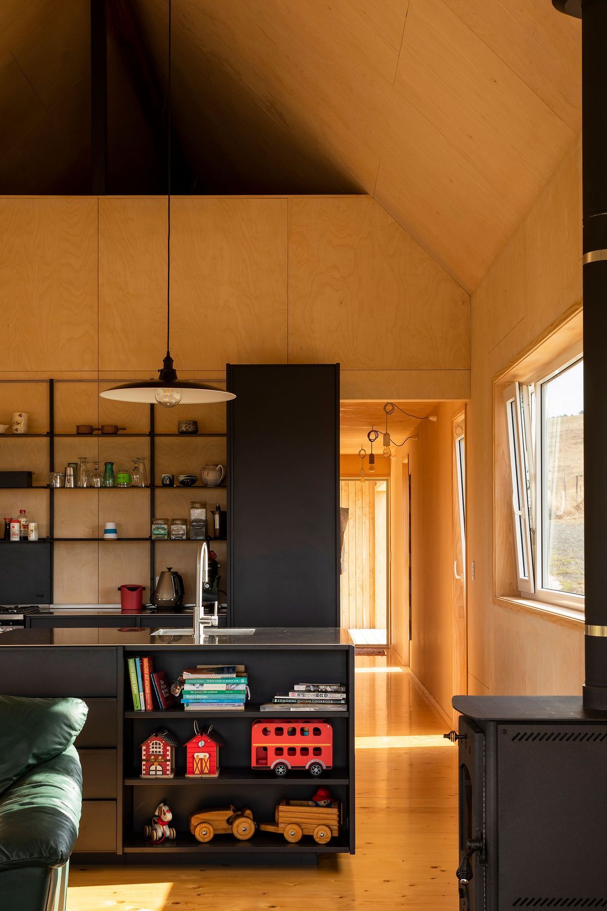 An all-black kitchen provides a strong contrast against the light timbers.