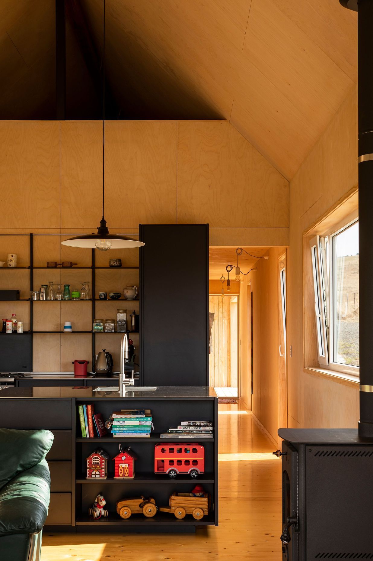 An all-black kitchen provides a strong contrast against the light timbers.