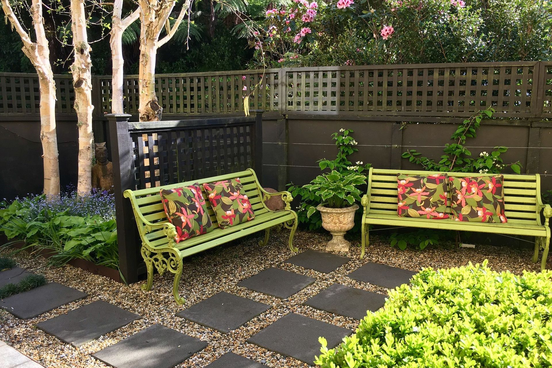 Garden seat with trellis fence and paved pathway to birch tree garden