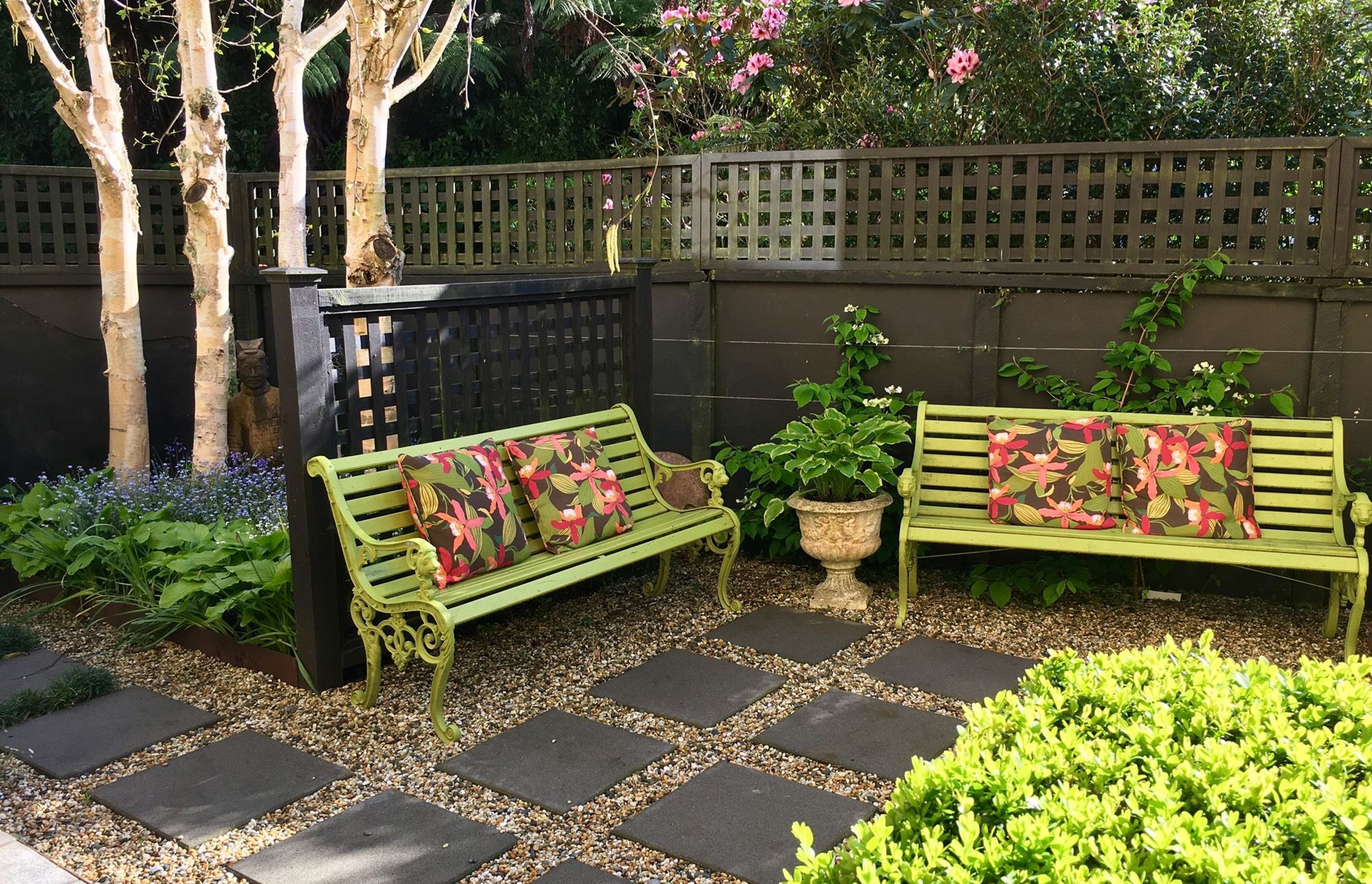 Garden seat with trellis fence and paved pathway to birch tree garden