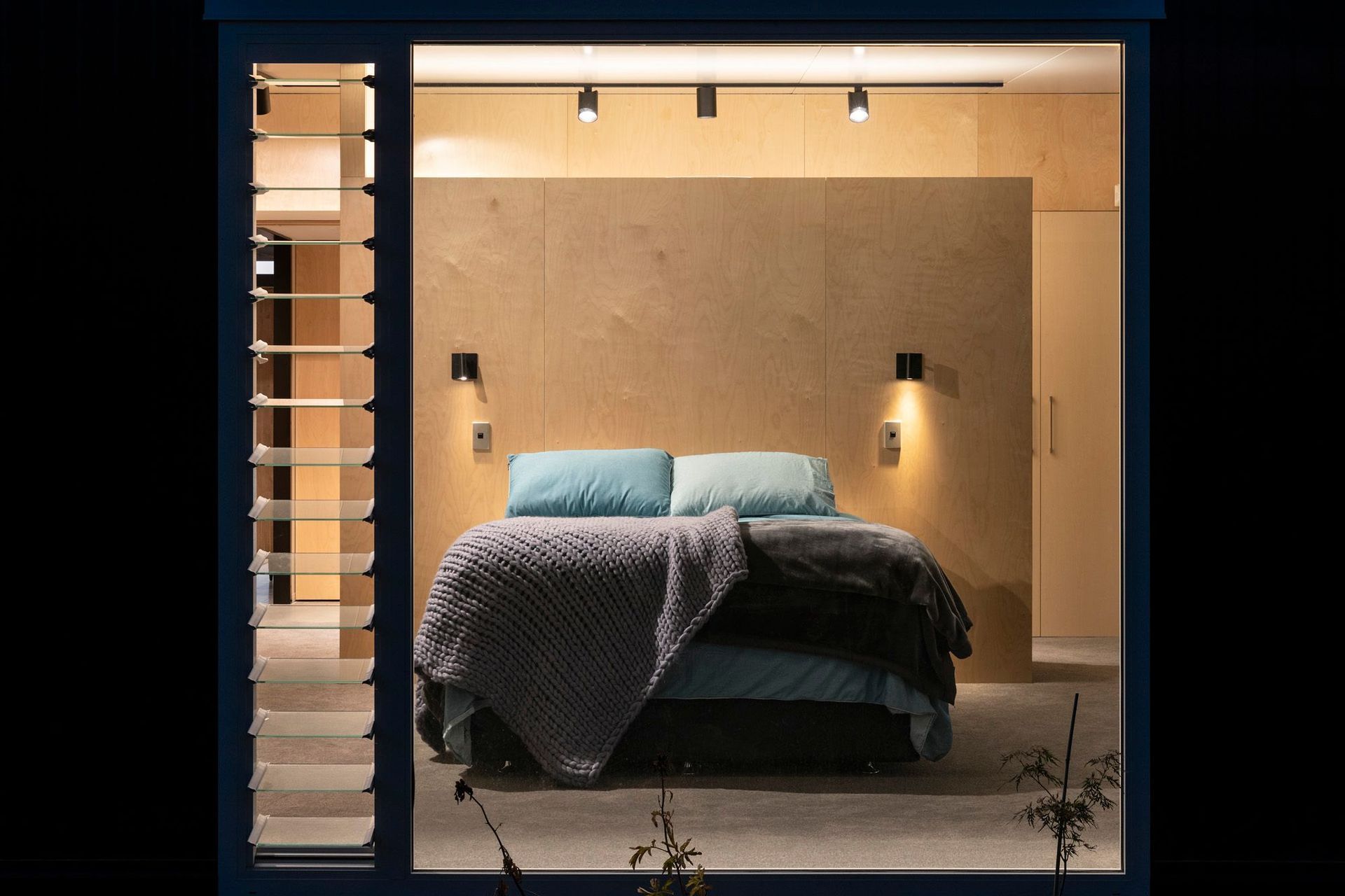 The master bedroom has a walk-in wardrobe created by a plywood divider, so it remains light and open. Photograph: Simon Devitt.