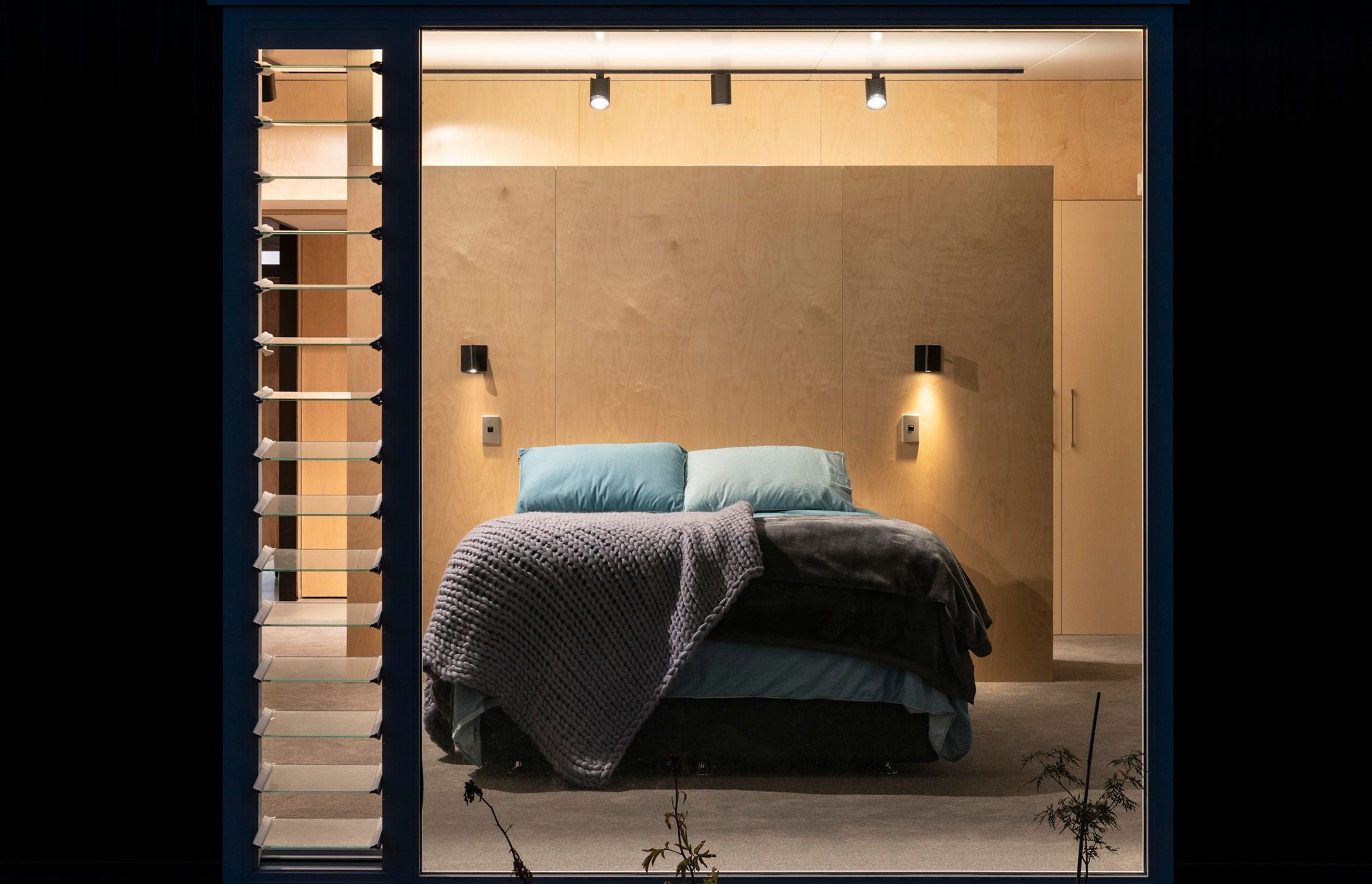 The master bedroom has a walk-in wardrobe created by a plywood divider, so it remains light and open. Photograph: Simon Devitt.