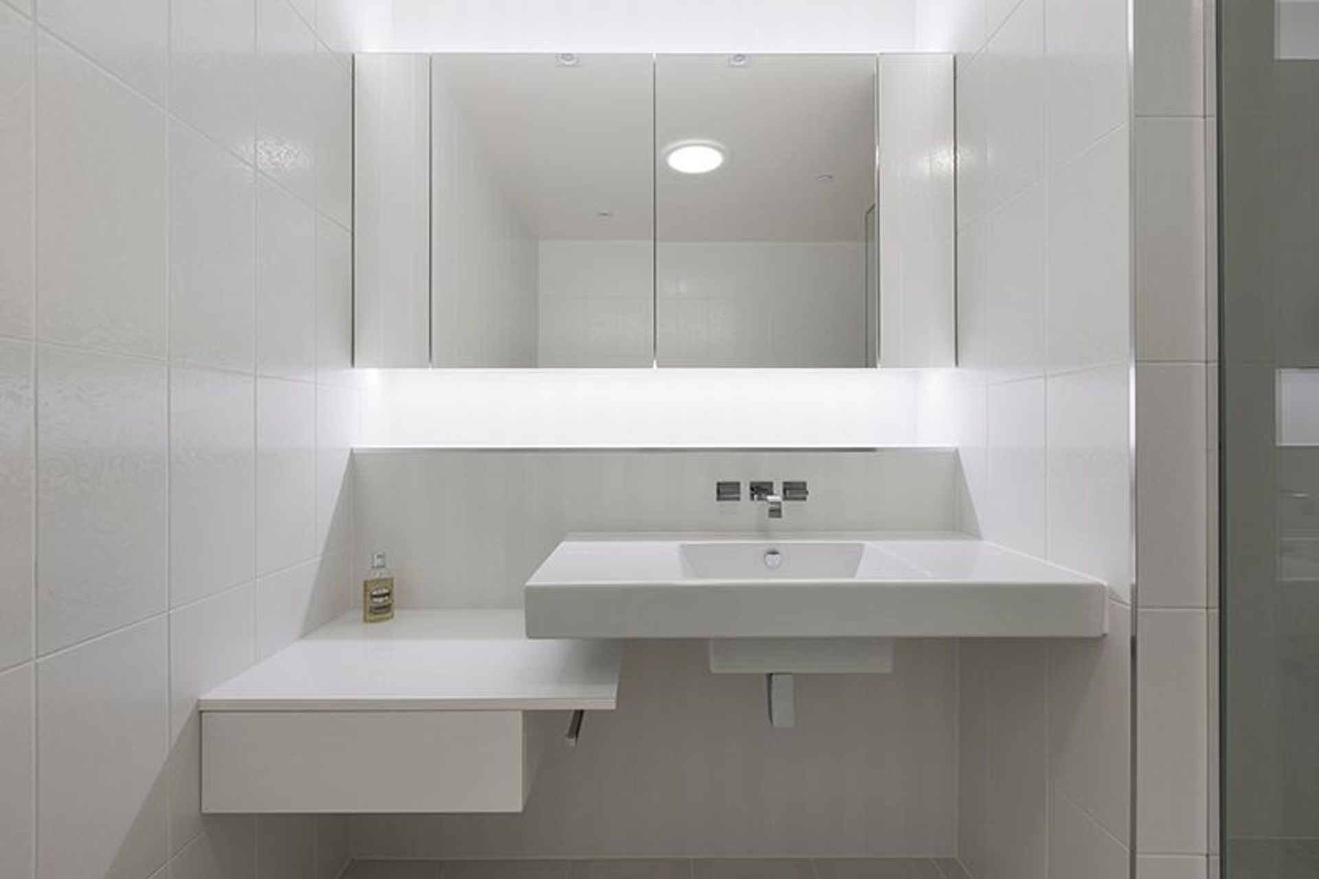 Bright white internal guest bathroom, recessed mirror cabinets with LED lighting detail
