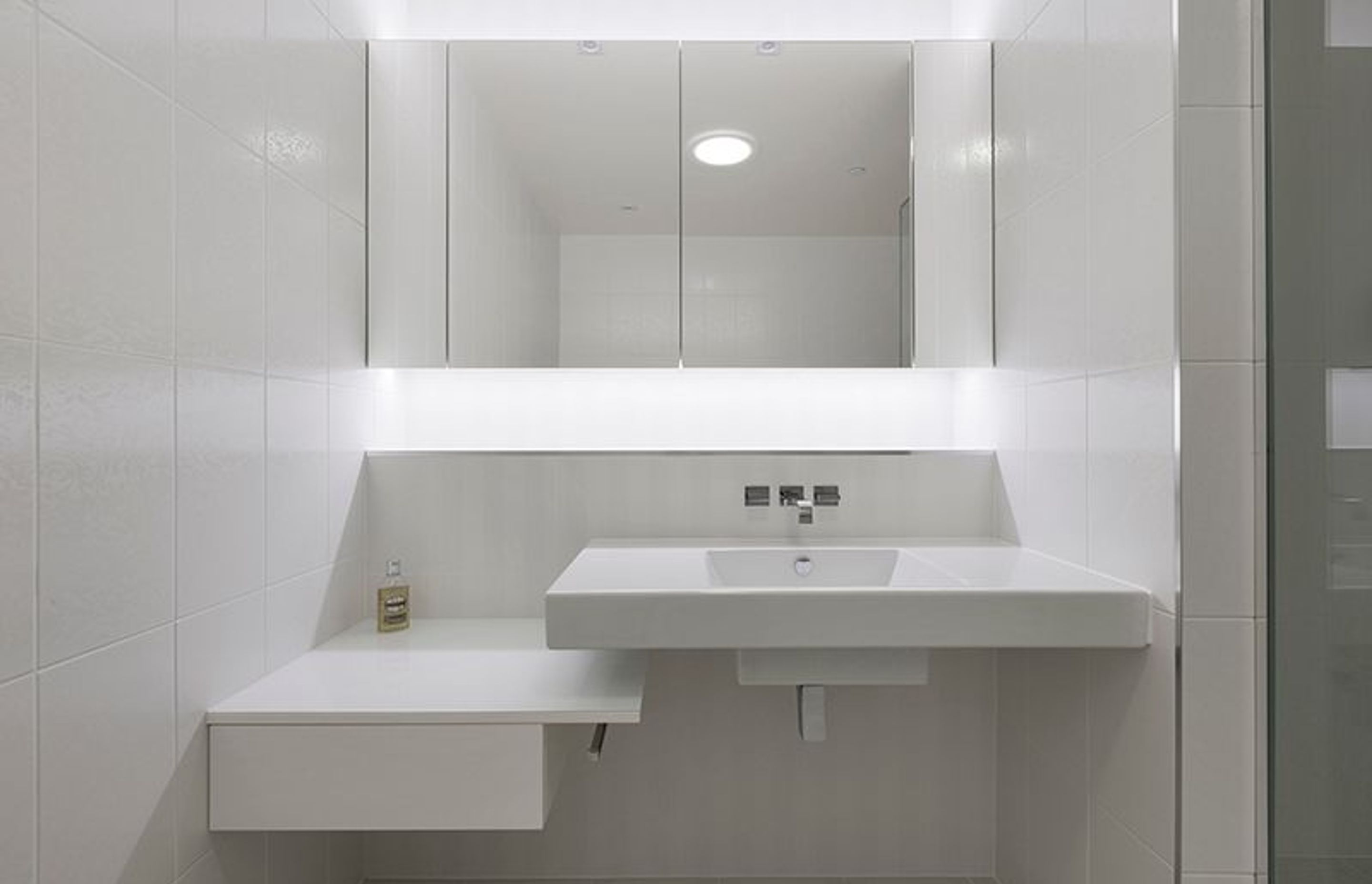 Bright white internal guest bathroom, recessed mirror cabinets with LED lighting detail