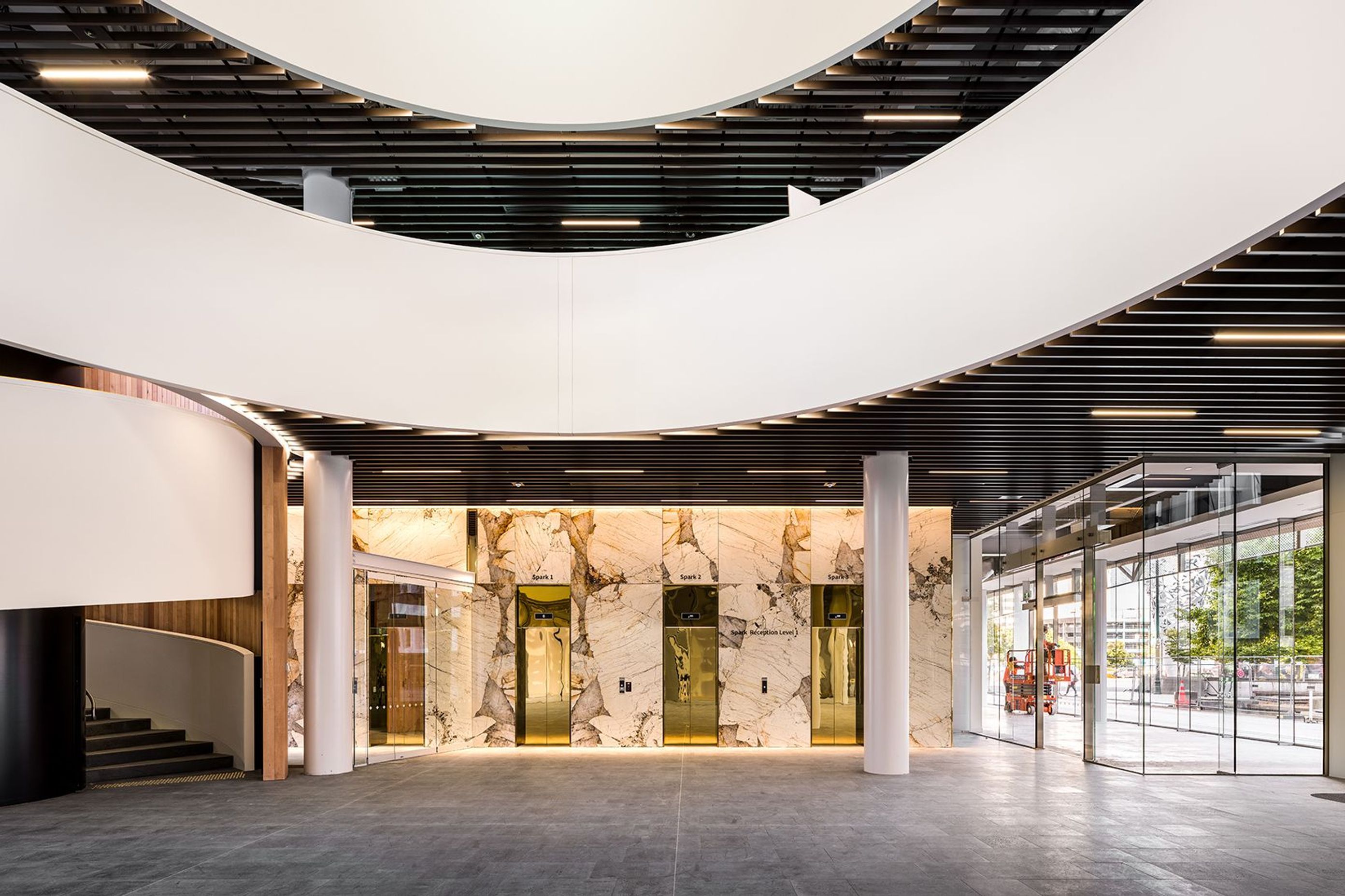 Filled with shops, bars and restaurants, the ground floor atrium features a dramatic spiral staircase in the public area, seen here with shiny reflective lift doors below.