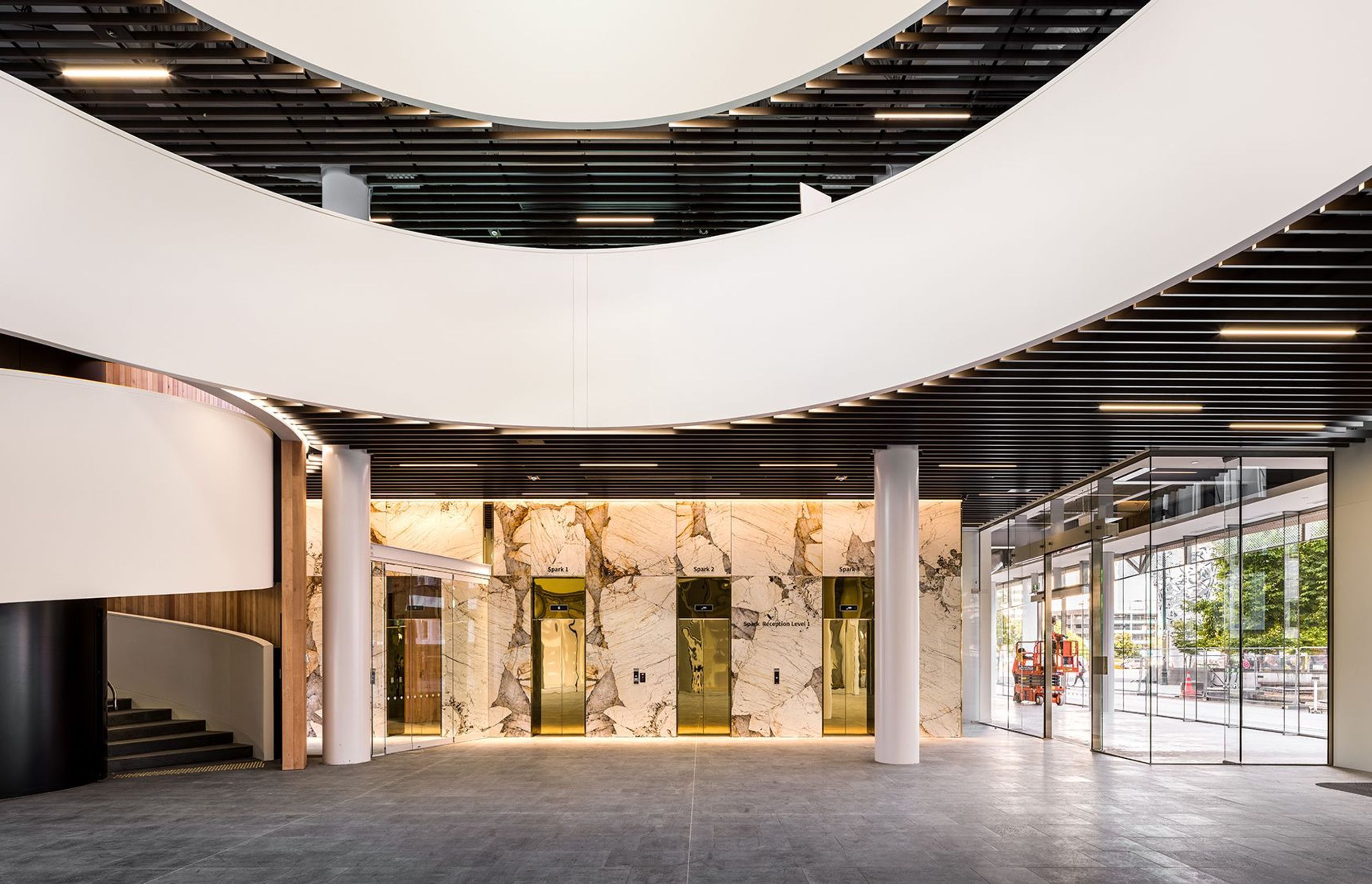Filled with shops, bars and restaurants, the ground floor atrium features a dramatic spiral staircase in the public area, seen here with shiny reflective lift doors below.