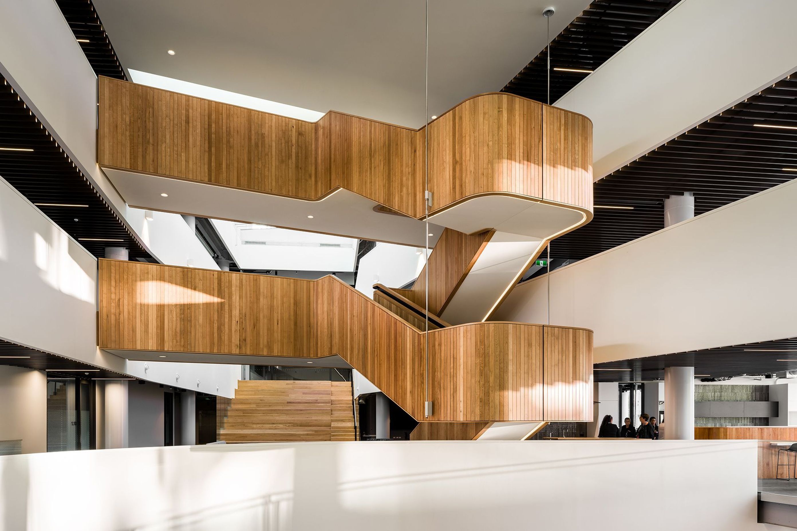 Timber panelling in the interior adds warmth and texture, including a hanging timber staircase inserted into the central void.