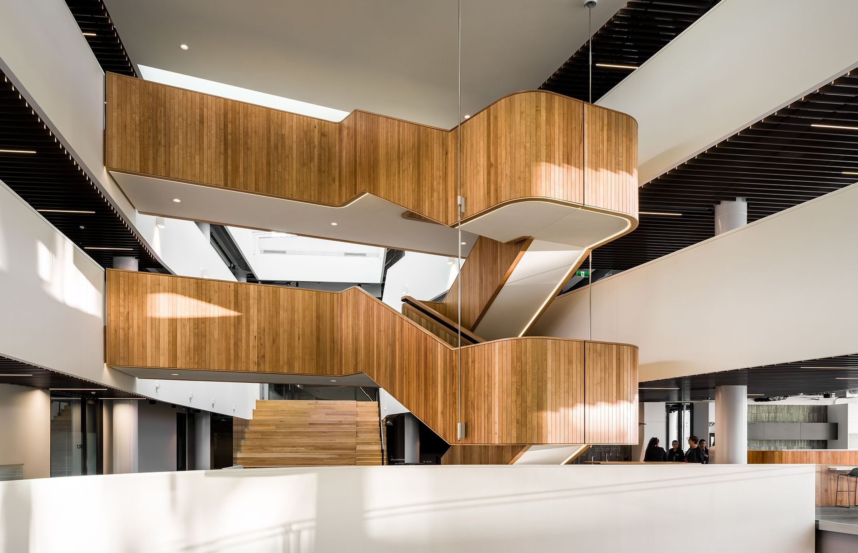 Timber panelling in the interior adds warmth and texture, including a hanging timber staircase inserted into the central void.
