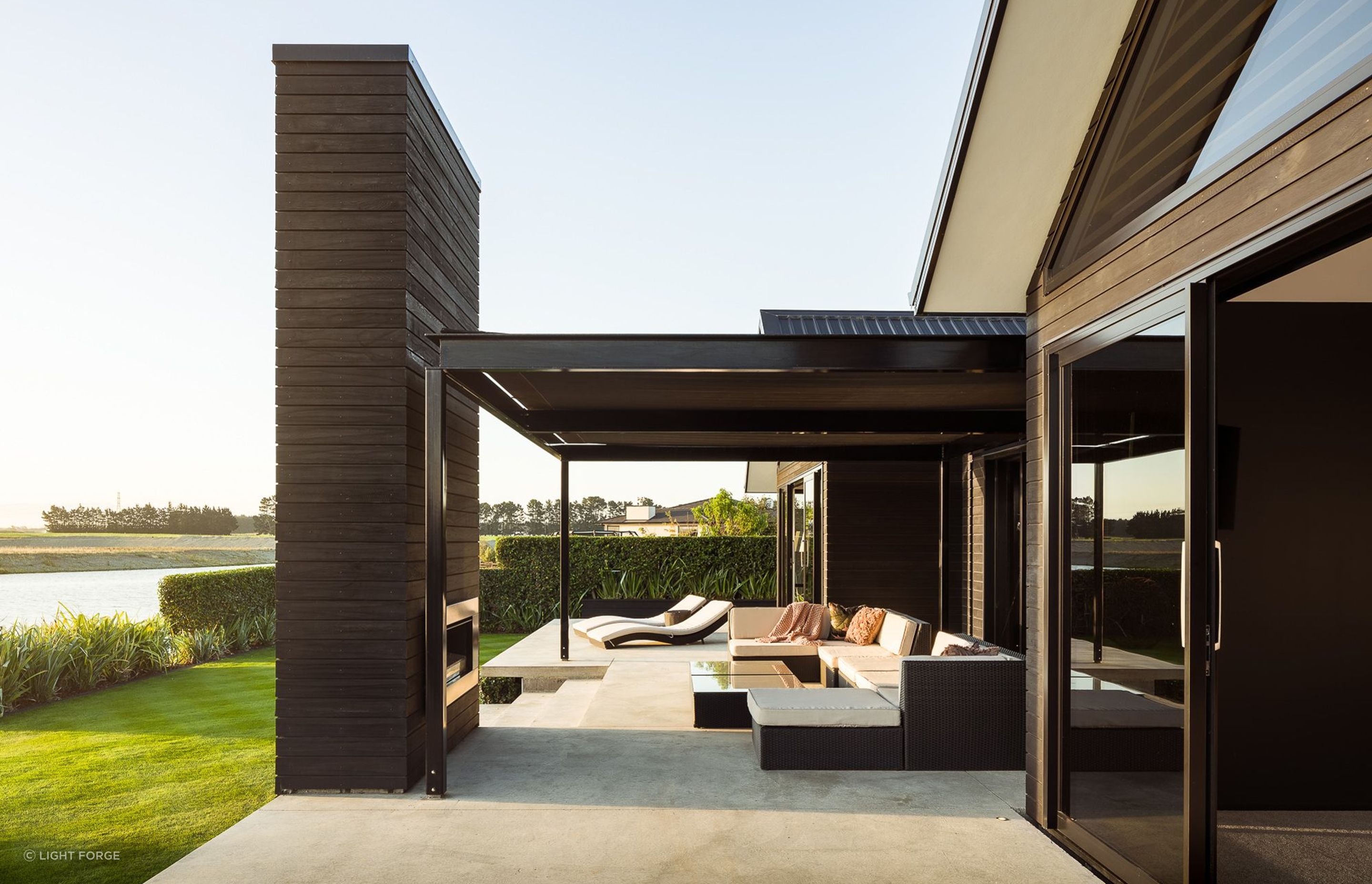 An outdoor fireplace, clad in dark-stained cedar echoes two other fireplaces inside the home.