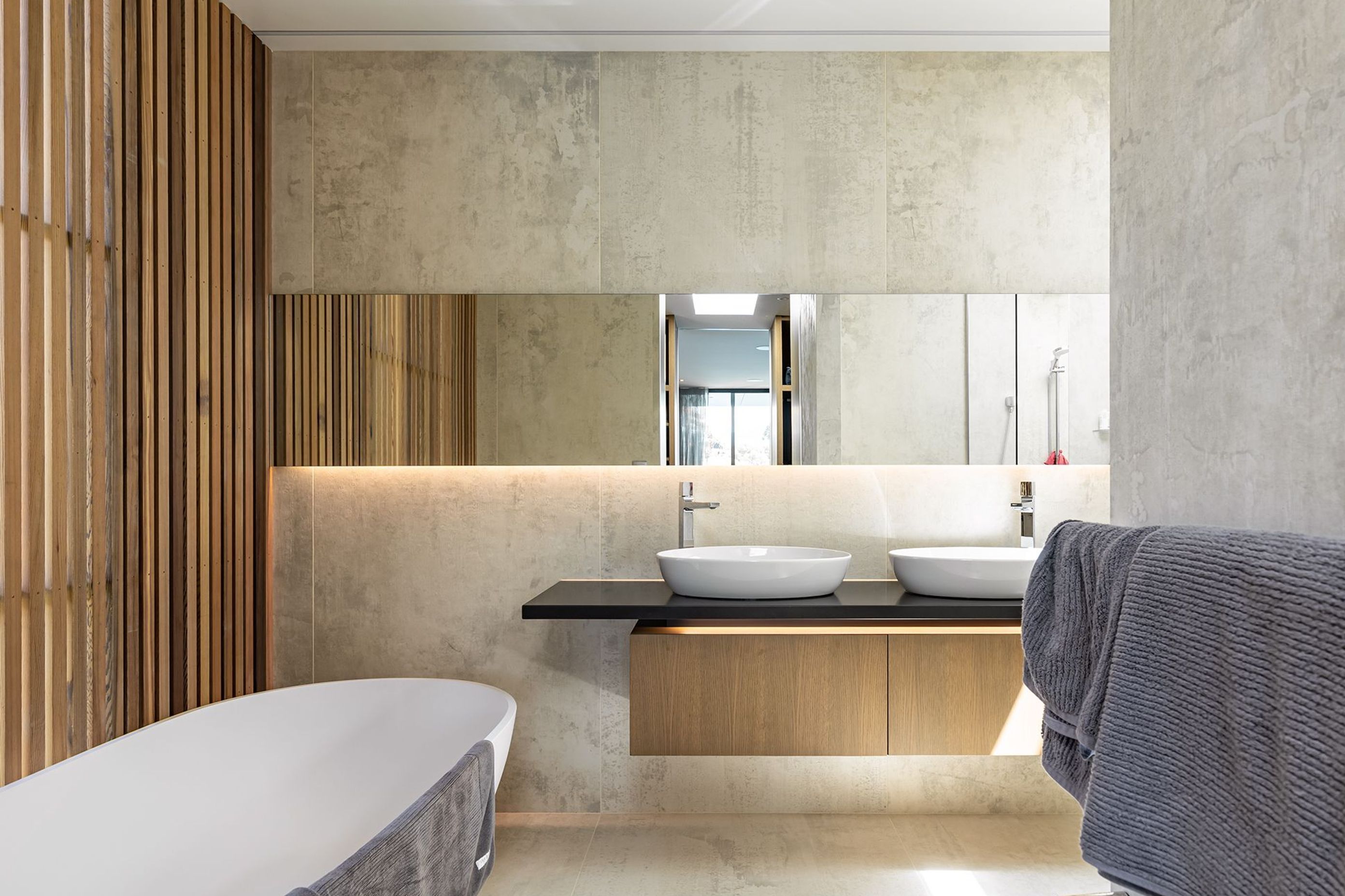Cedar panelling has been continued into the bathroom, diffusing the light through the window and adding warmth to the harder surfaces.