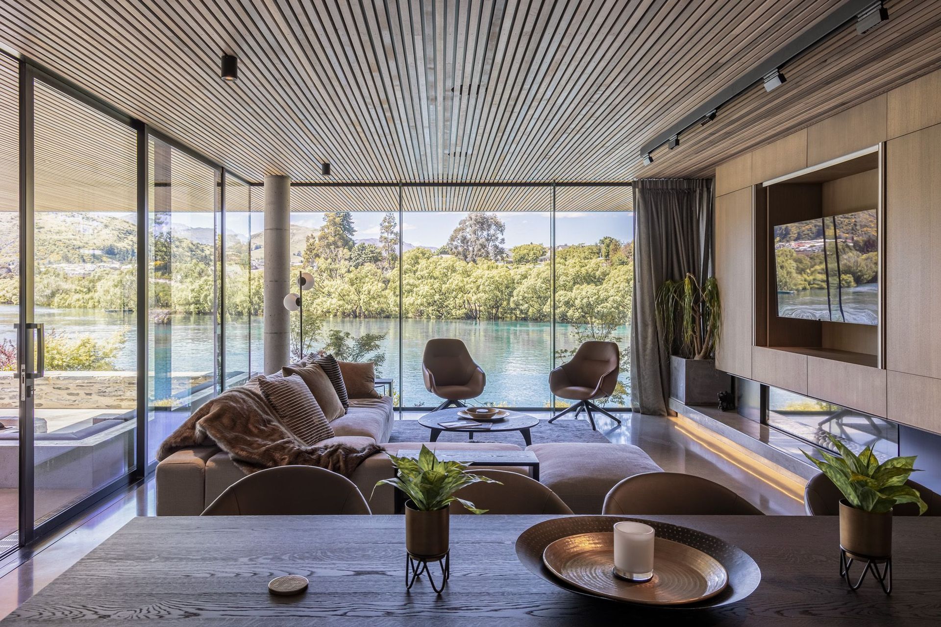 On the ground floor, the lounge area feels as if it sits right over the lake and features bespoke cabinetry along one wall with a built-in frameless fireplace.