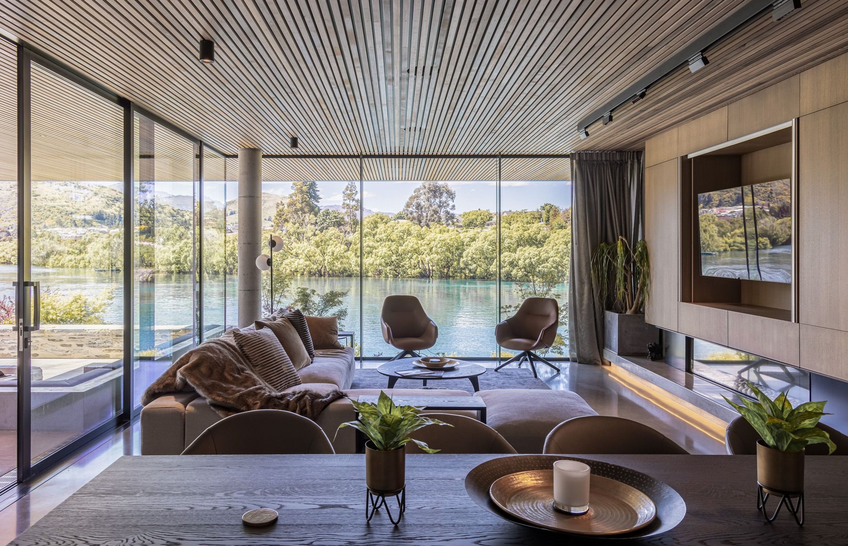 On the ground floor, the lounge area feels as if it sits right over the lake and features bespoke cabinetry along one wall with a built-in frameless fireplace.