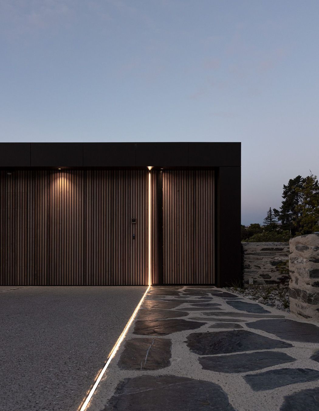 At night, a saber of light travels down the discreet garage doors and along the entry pathway.