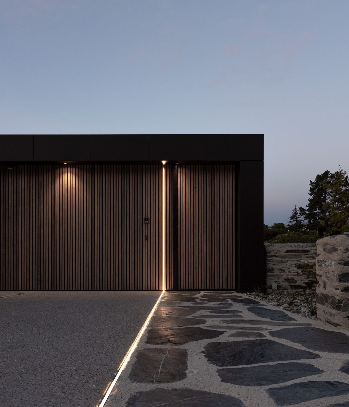 At night, a saber of light travels down the discreet garage doors and along the entry pathway.