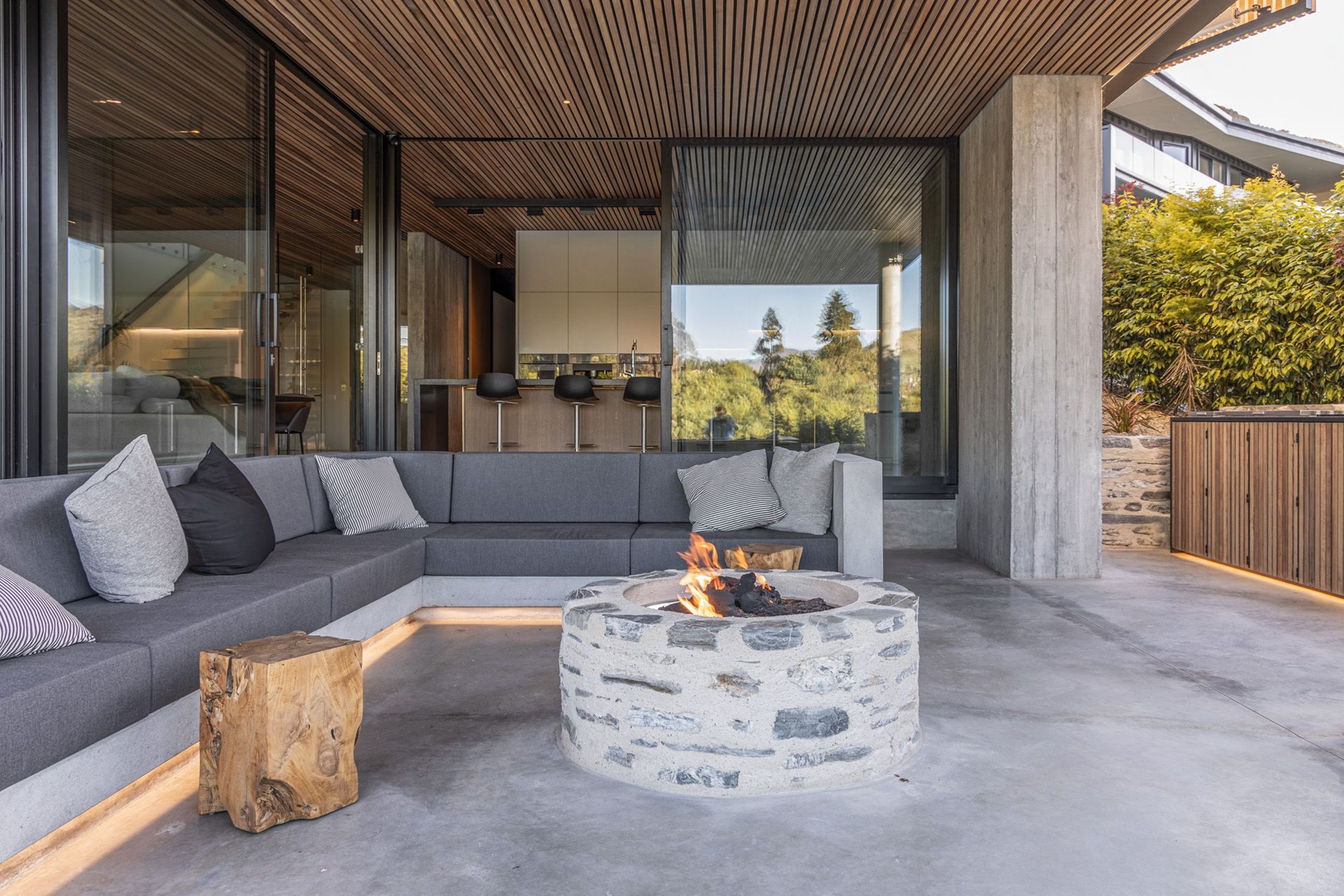 Underneath the cantilevered roof, the sheltered outdoor room features built-in furniture and a schist fire pit.