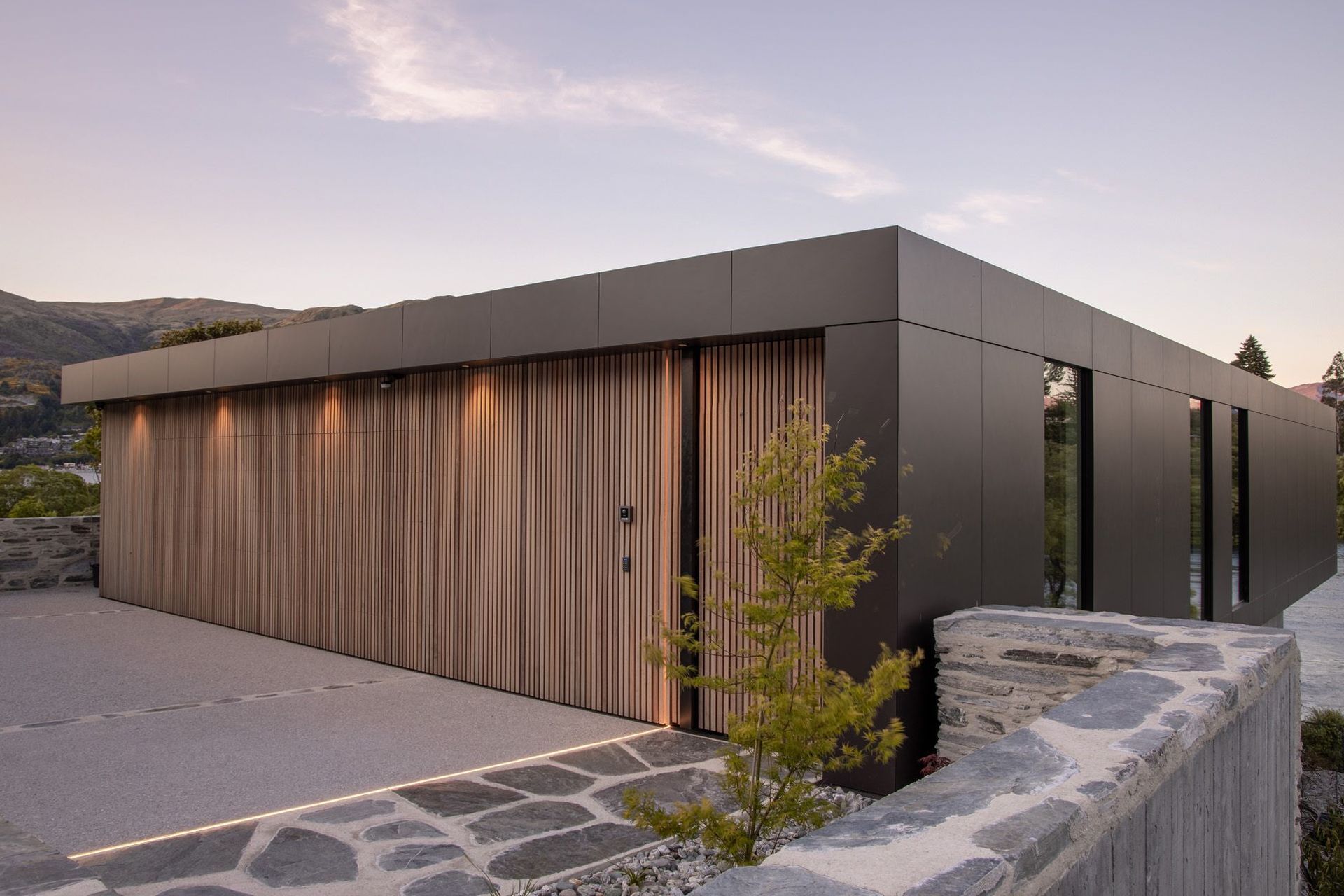 Cedar walls have secret doors, seen here in the garage and front entrance, surrounded by local schist walls.