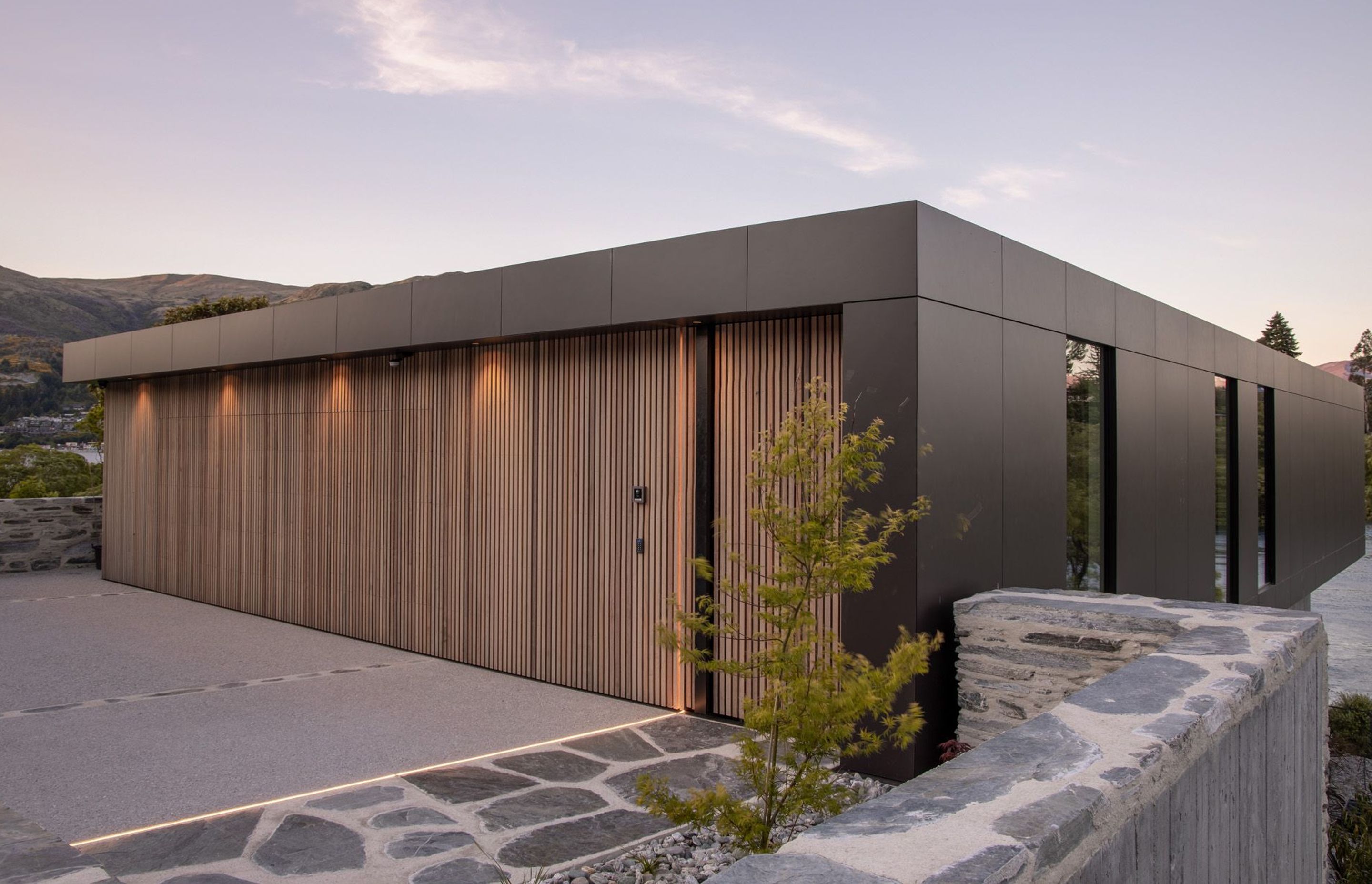 Cedar walls have secret doors, seen here in the garage and front entrance, surrounded by local schist walls.