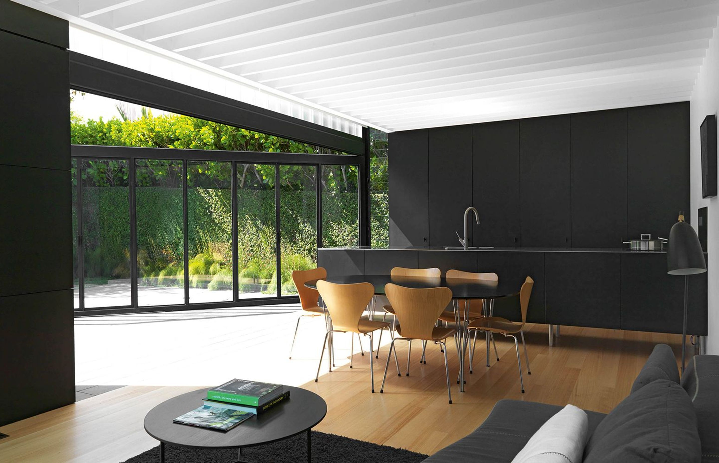 A galley kitchen of powdercoated steel cabinetry and stainless steel with concealed appliances runs across the end of the open-plan living space.