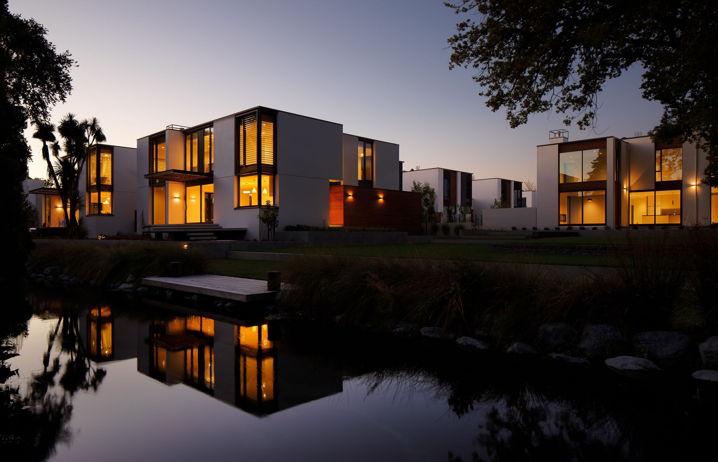 In the darkness the houses cast perfect reflections onto the river yet despite their illumination they remain overshadowed by the reflections of the vast tree canopies and planting that dance larger than life across the water as they move in the breeze.