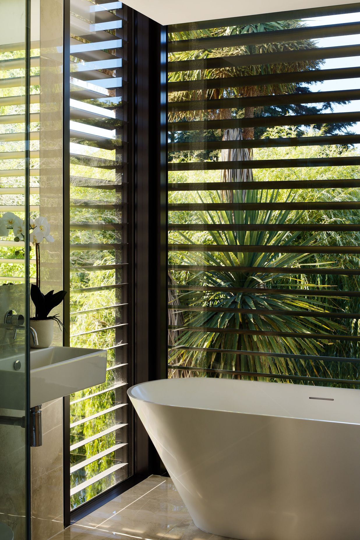 Black aluminium louvres contrast the cedar and plastered block of the exterior.