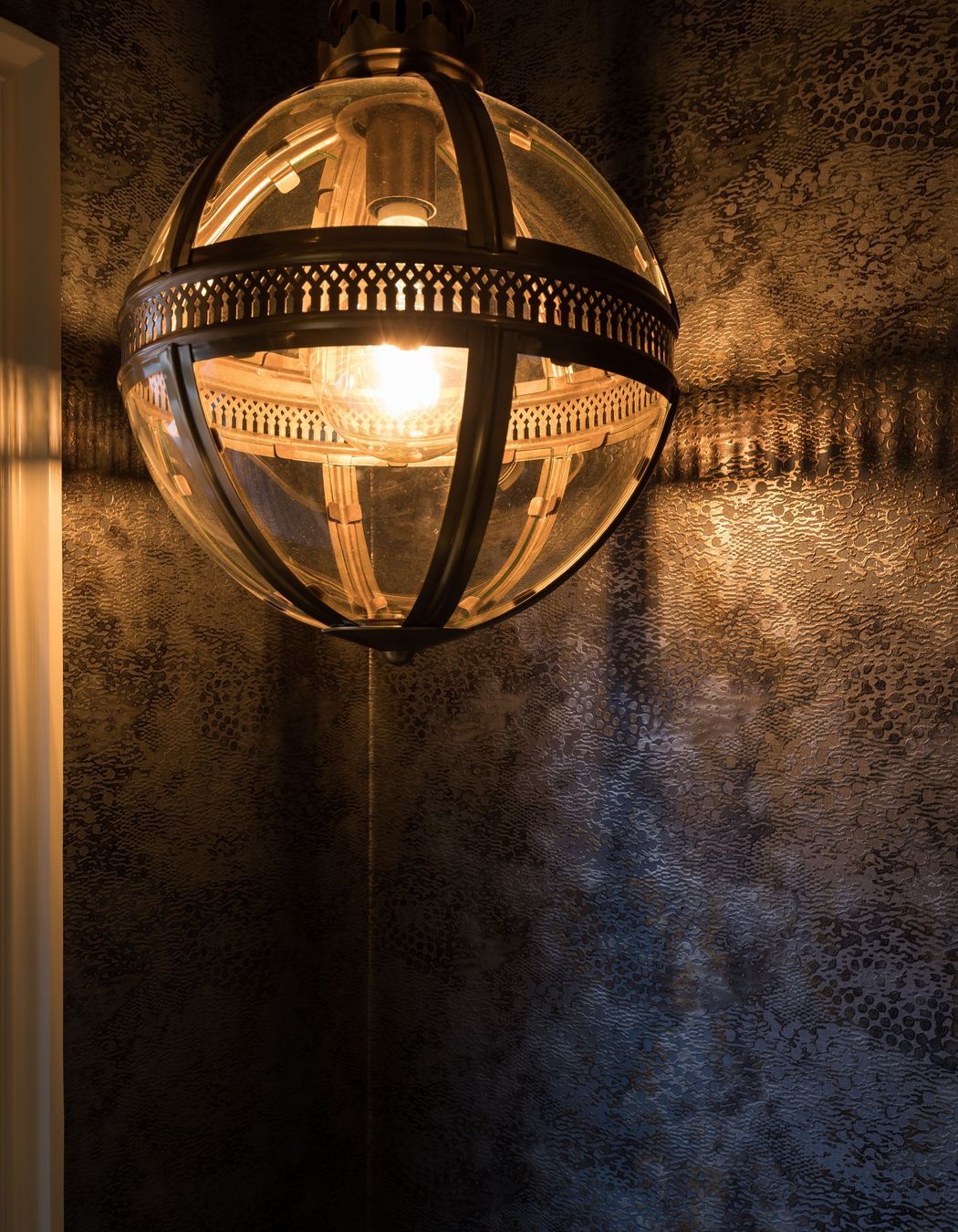 Combined Laundry and Powder Room - Cassamance textured gold and balck wallpaper, highlighted by the gold pendant light