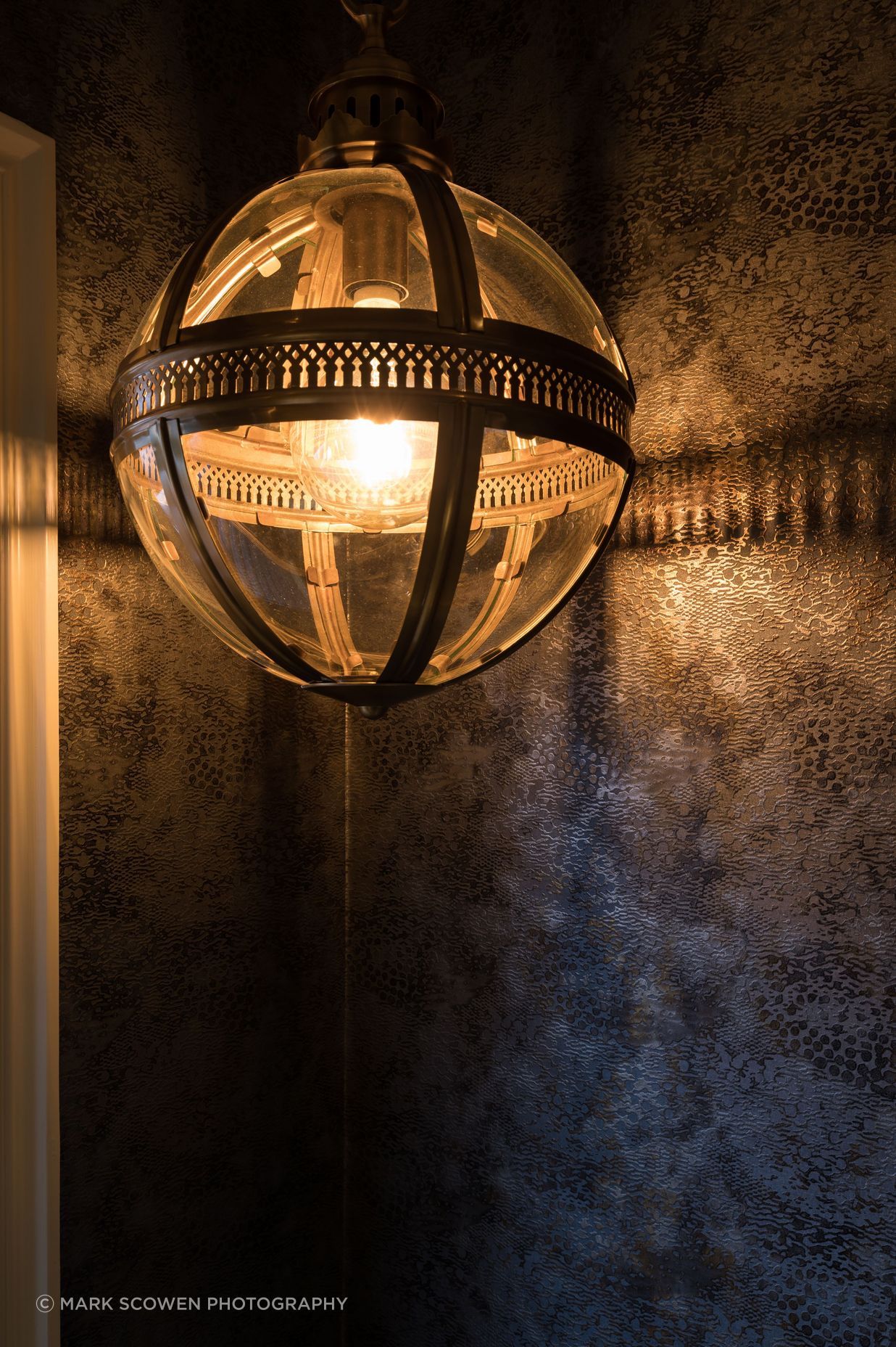 Combined Laundry and Powder Room - Cassamance textured gold and balck wallpaper, highlighted by the gold pendant light