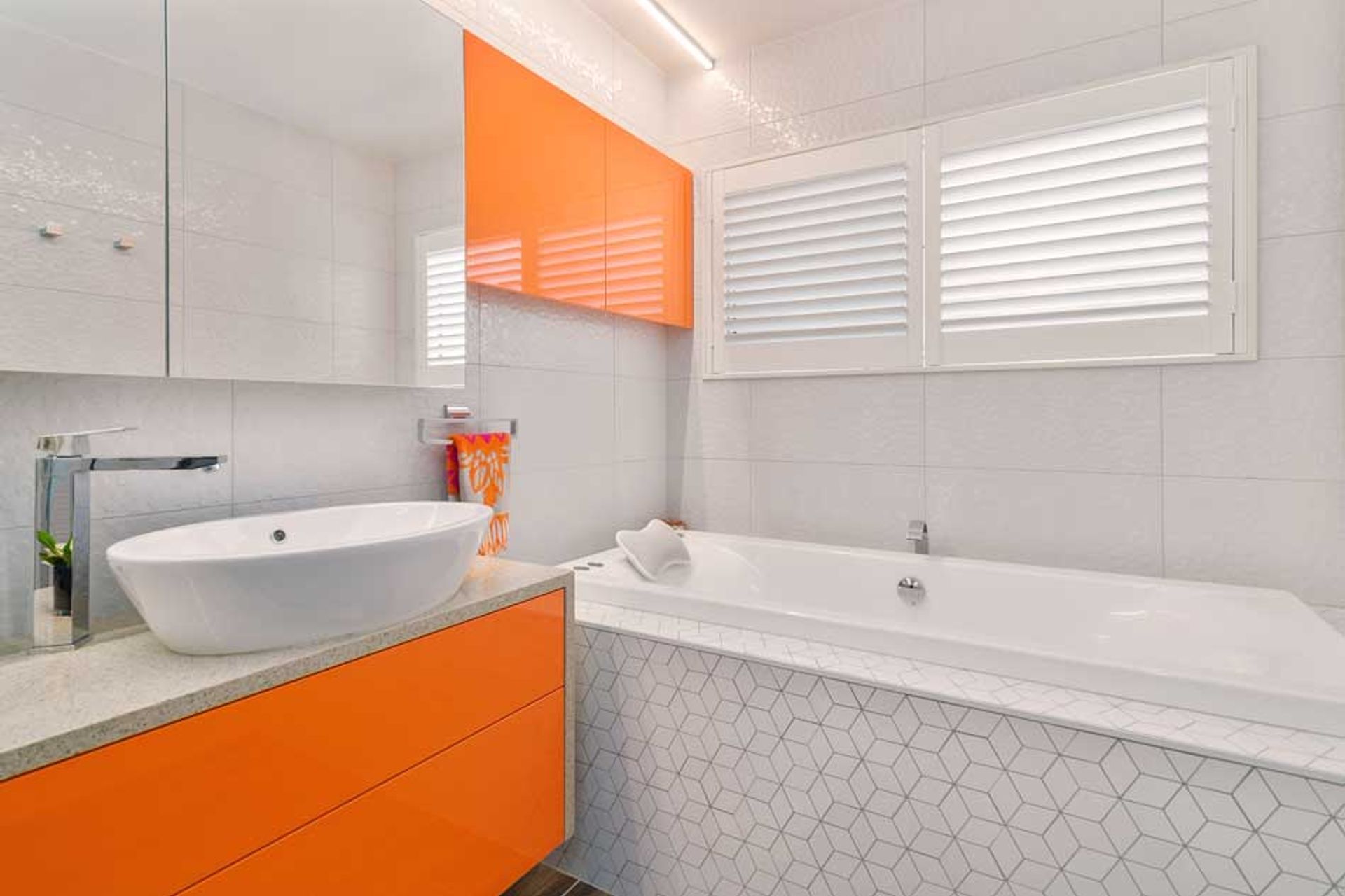 The hexagon design is in both the wall tiles and further enhanced with the mosaic tiles around the bath