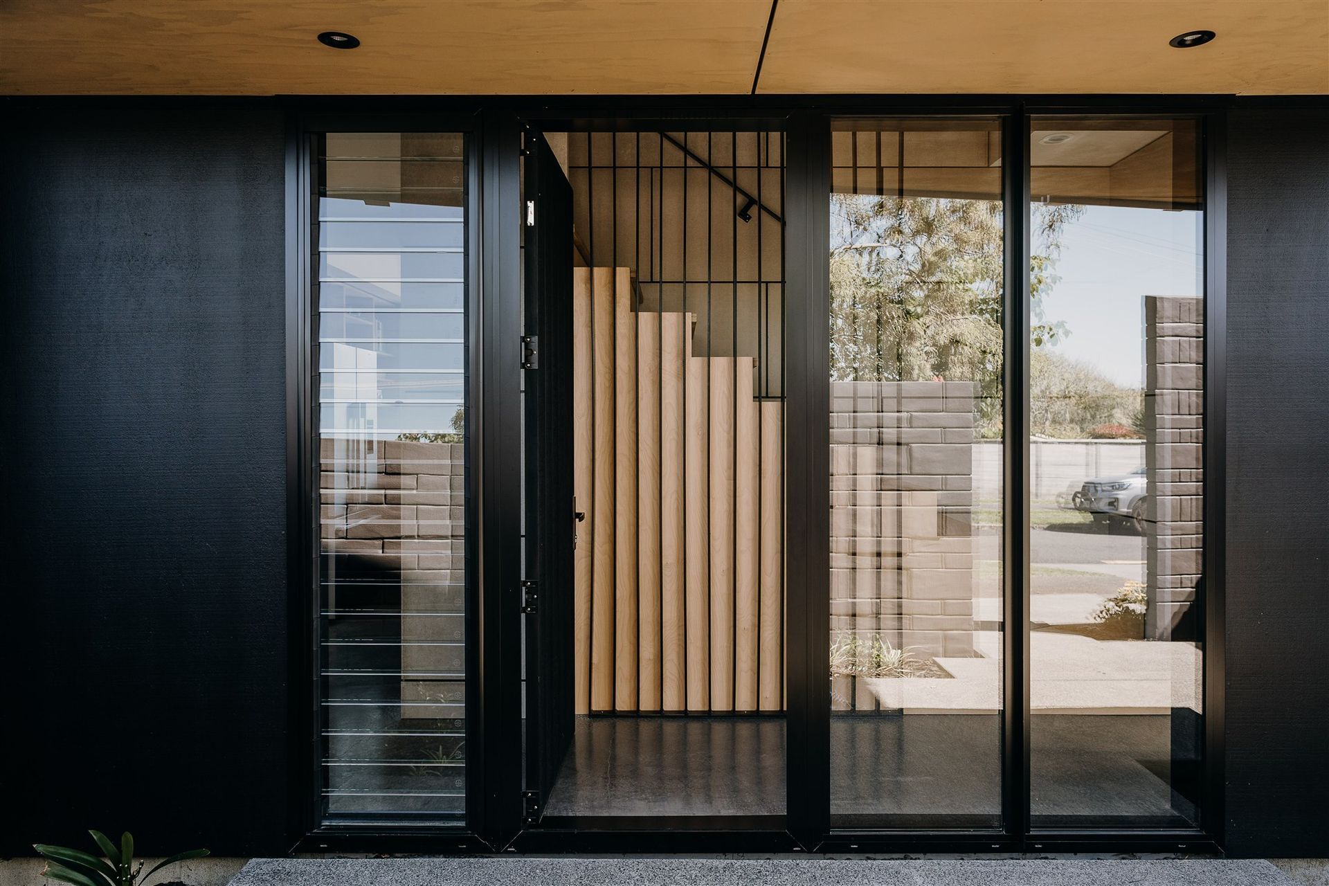 A floated concrete floor, black steel fins and a timber stair continue the material palette of the exterior.