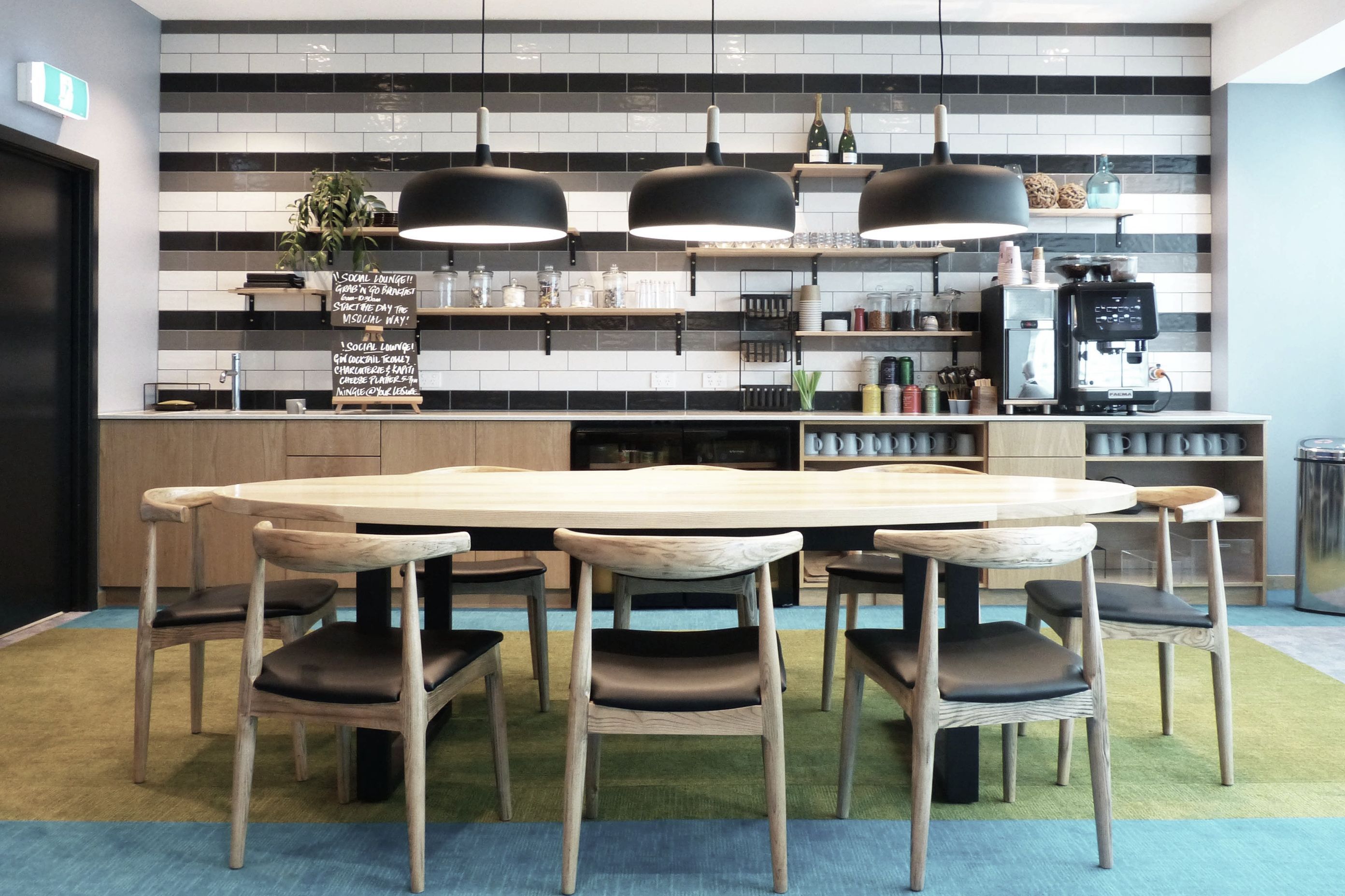 Ash and Californian oak timber finishes make durable and warm surfaces for the kitchen end of the lounge where guests can help themselves to coffee and quick meals. Ceramic subway tiles and exposed shelves make the kitchenette accessible and open.  
