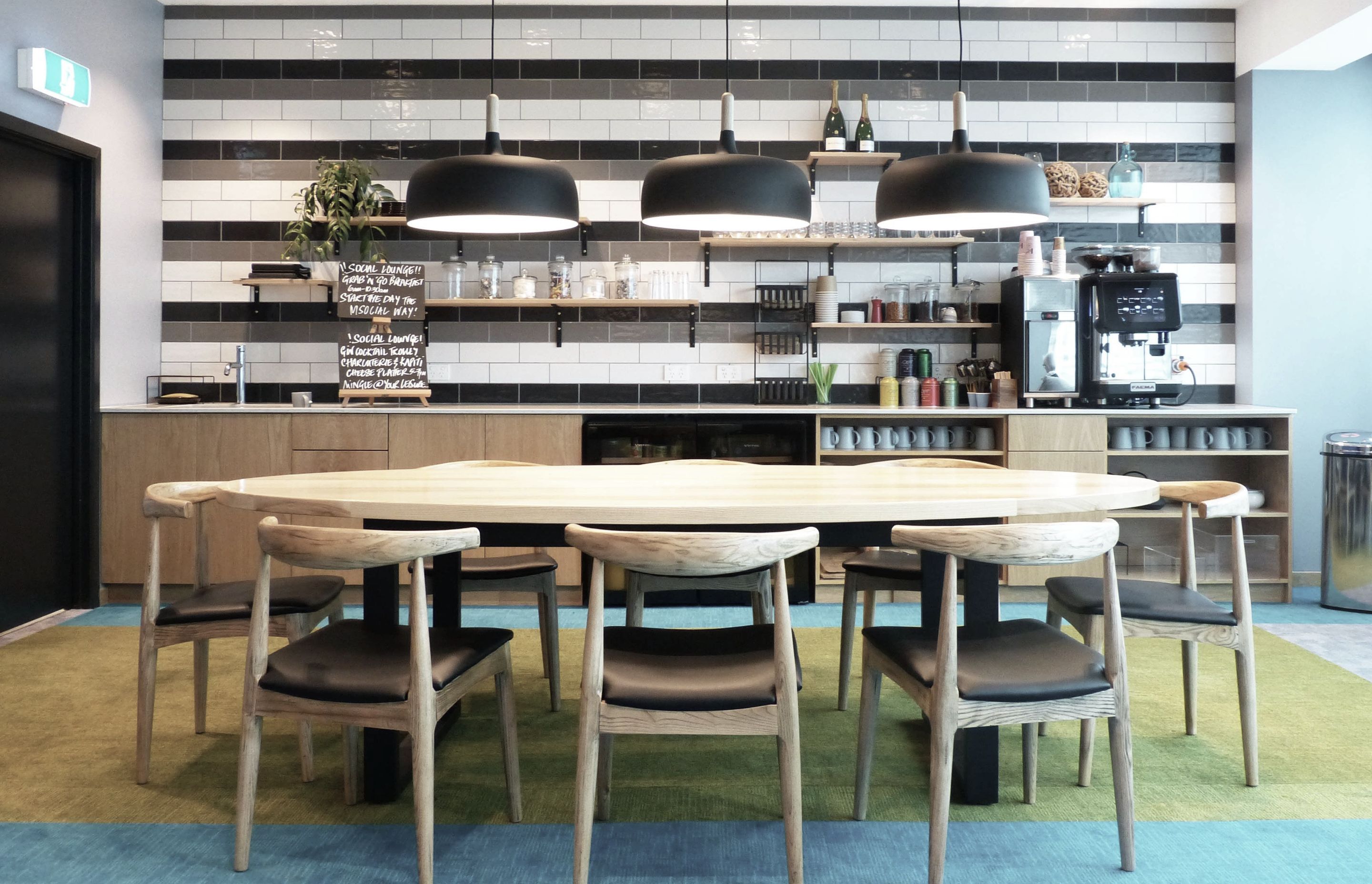 Ash and Californian oak timber finishes make durable and warm surfaces for the kitchen end of the lounge where guests can help themselves to coffee and quick meals. Ceramic subway tiles and exposed shelves make the kitchenette accessible and open.